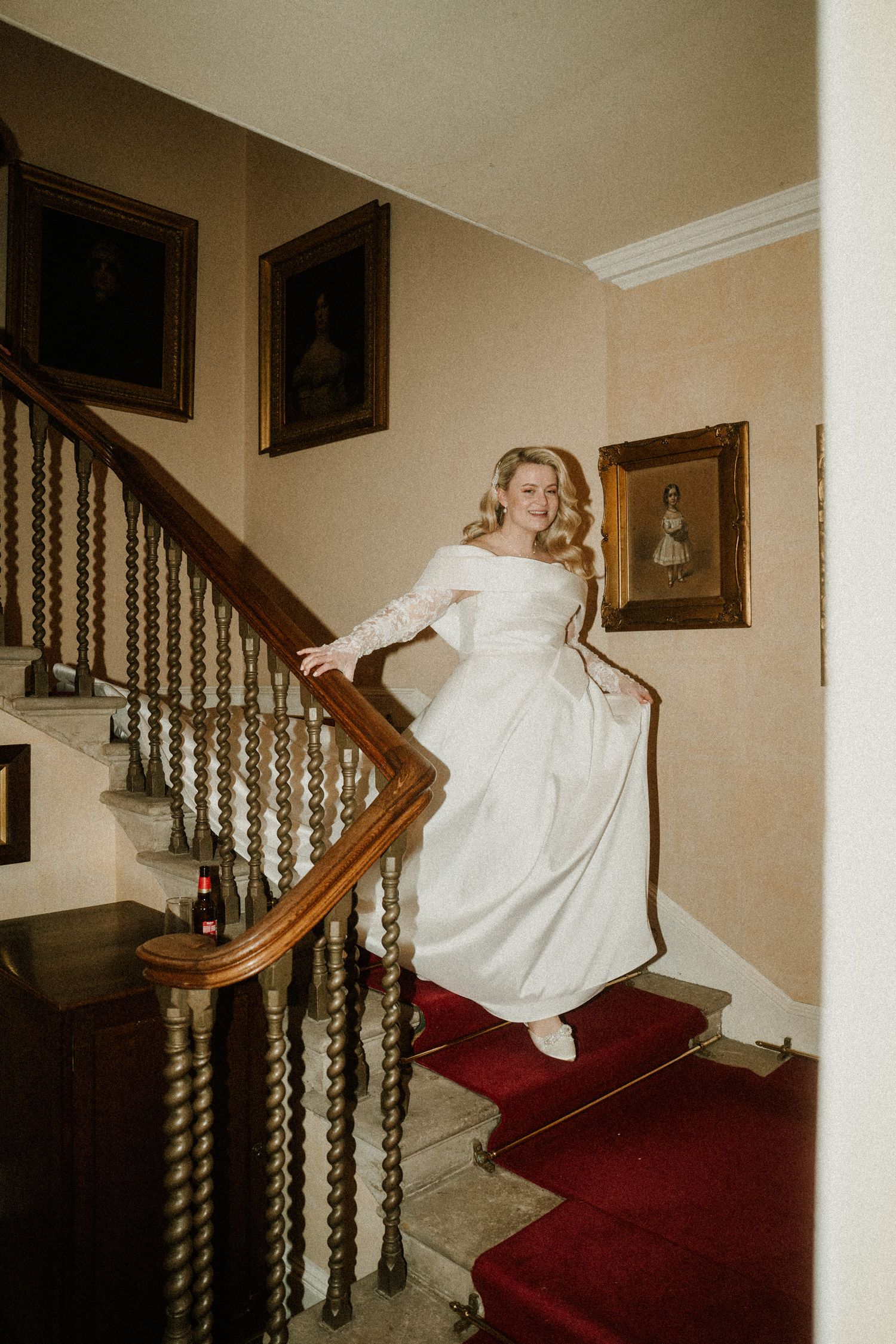 Classic wedding moment captured on a red-carpeted staircase in a historic interior.
