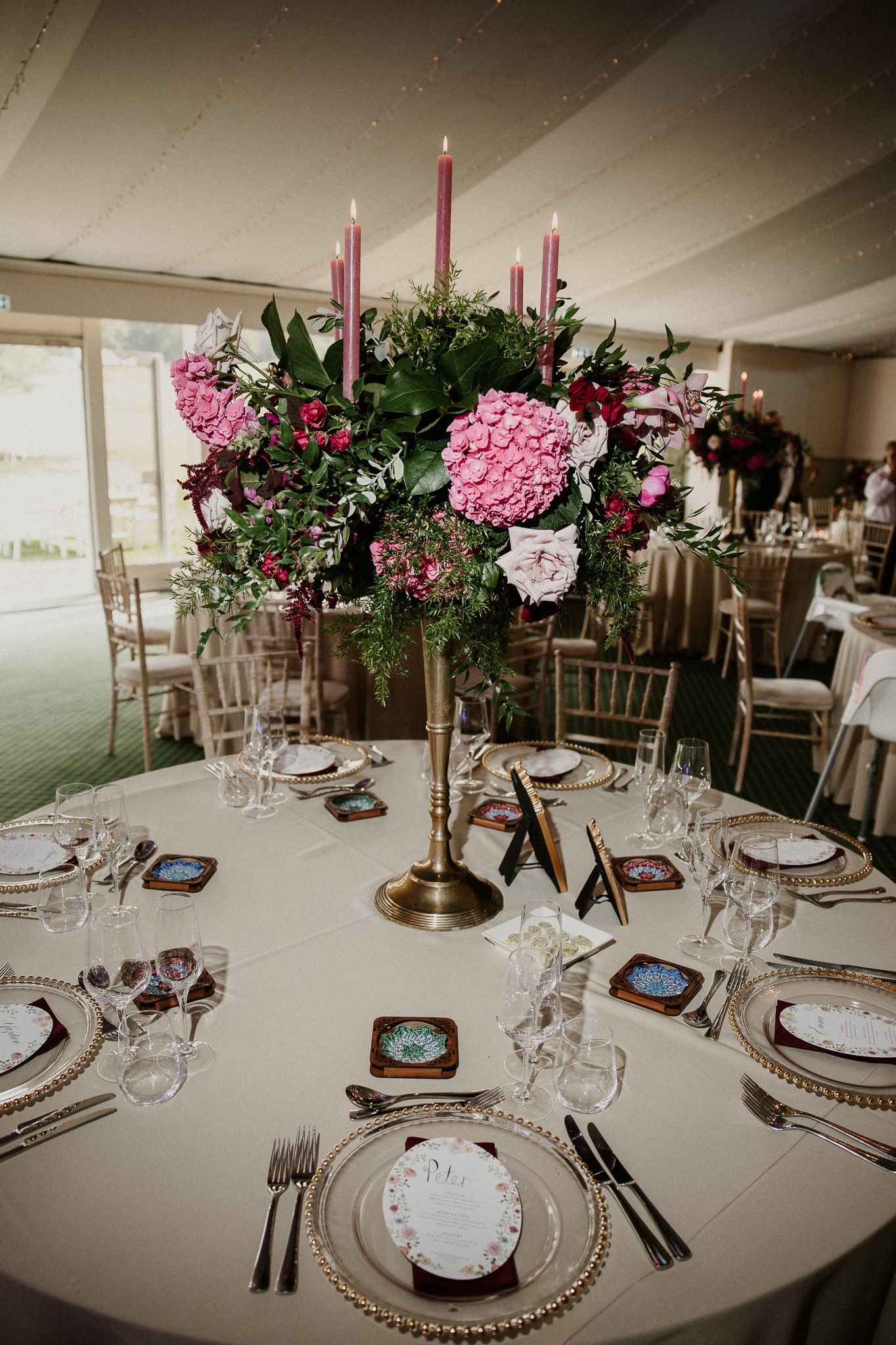 Elegant wedding reception table settings with pink floral centerpieces and tall candles.