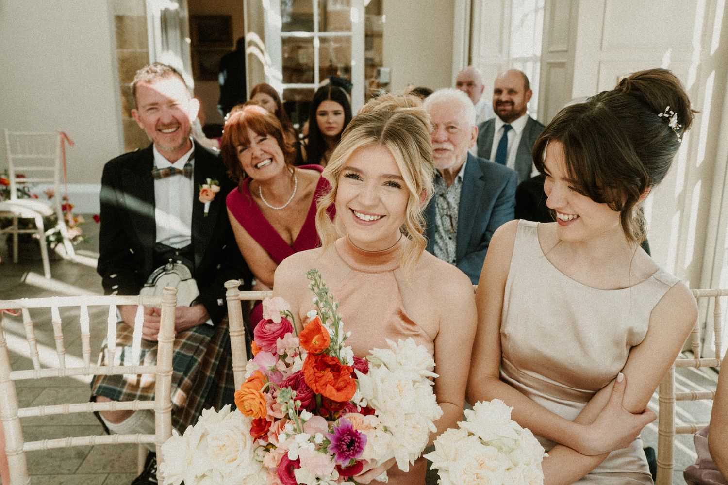 Wedding guests share joyful moments during the reception with colorful floral arrangements.