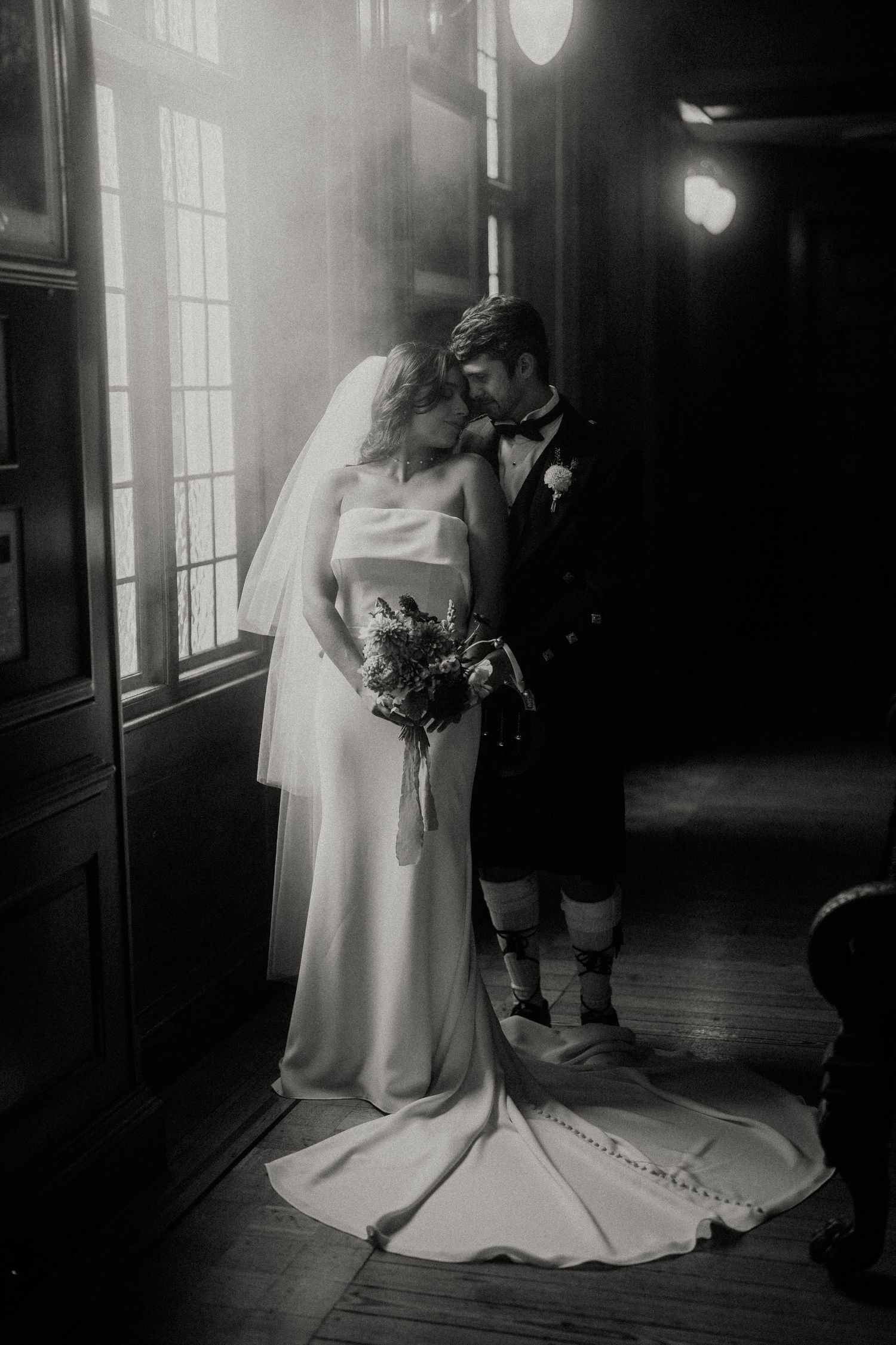 Artistic black and white wedding photos captured in a dimly lit hallway.