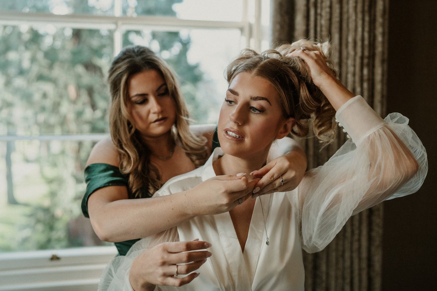 Two people share an intimate moment while getting ready in a sunlit room.