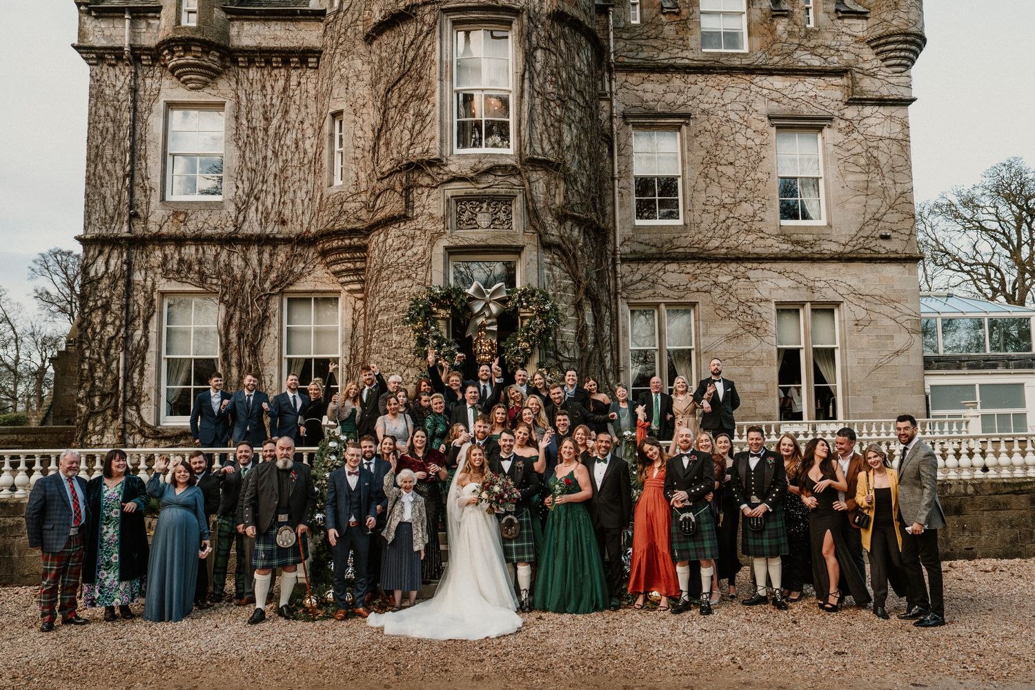 Large wedding party group photo in front of Scottish castle estate.