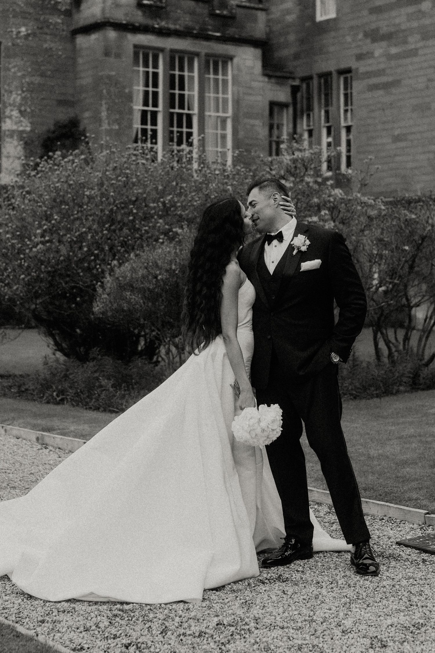 A black and white intimate wedding portrait against the backdrop of a historic castle.