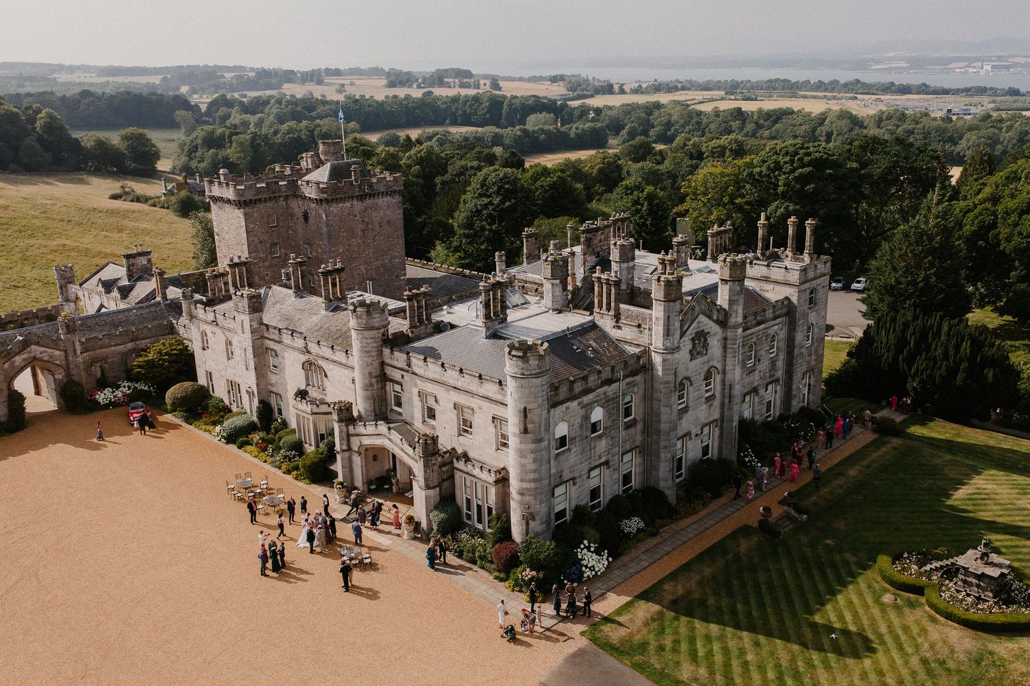 Aerial view of historic stone castle and surrounding grounds on wedding day.