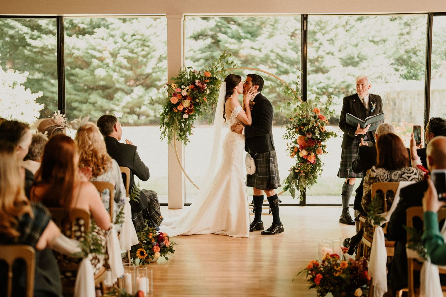 Elegant wedding ceremony setup with hanging floral arrangements and guests seated in rows.