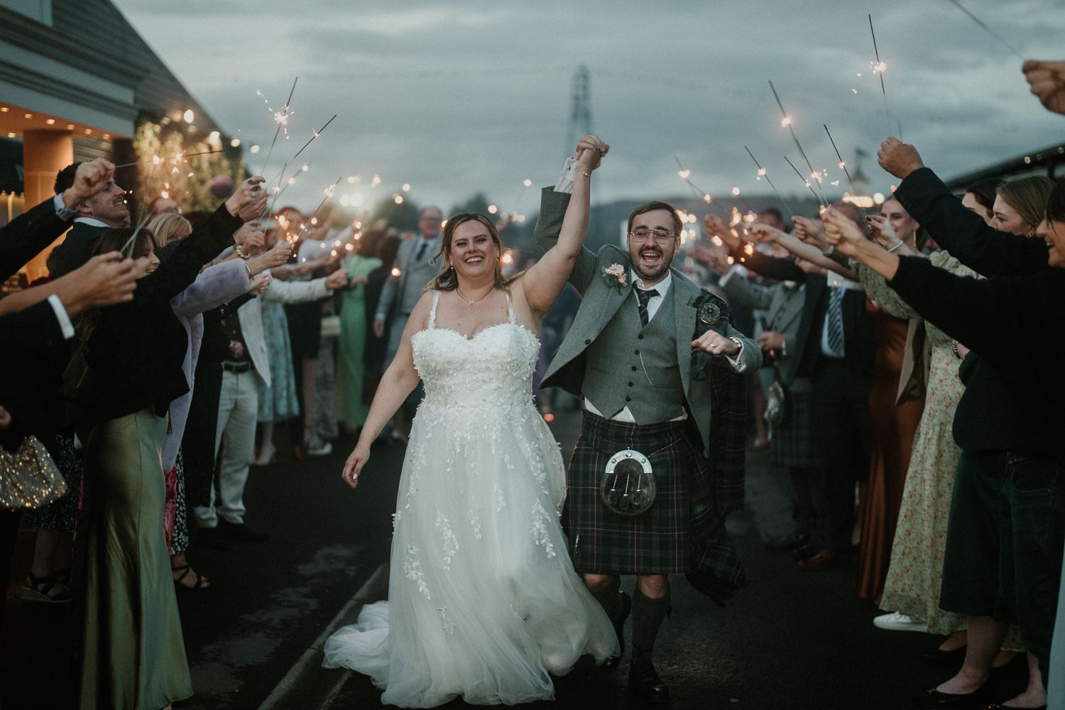 Wedding celebration with guests throwing confetti on an overcast evening.