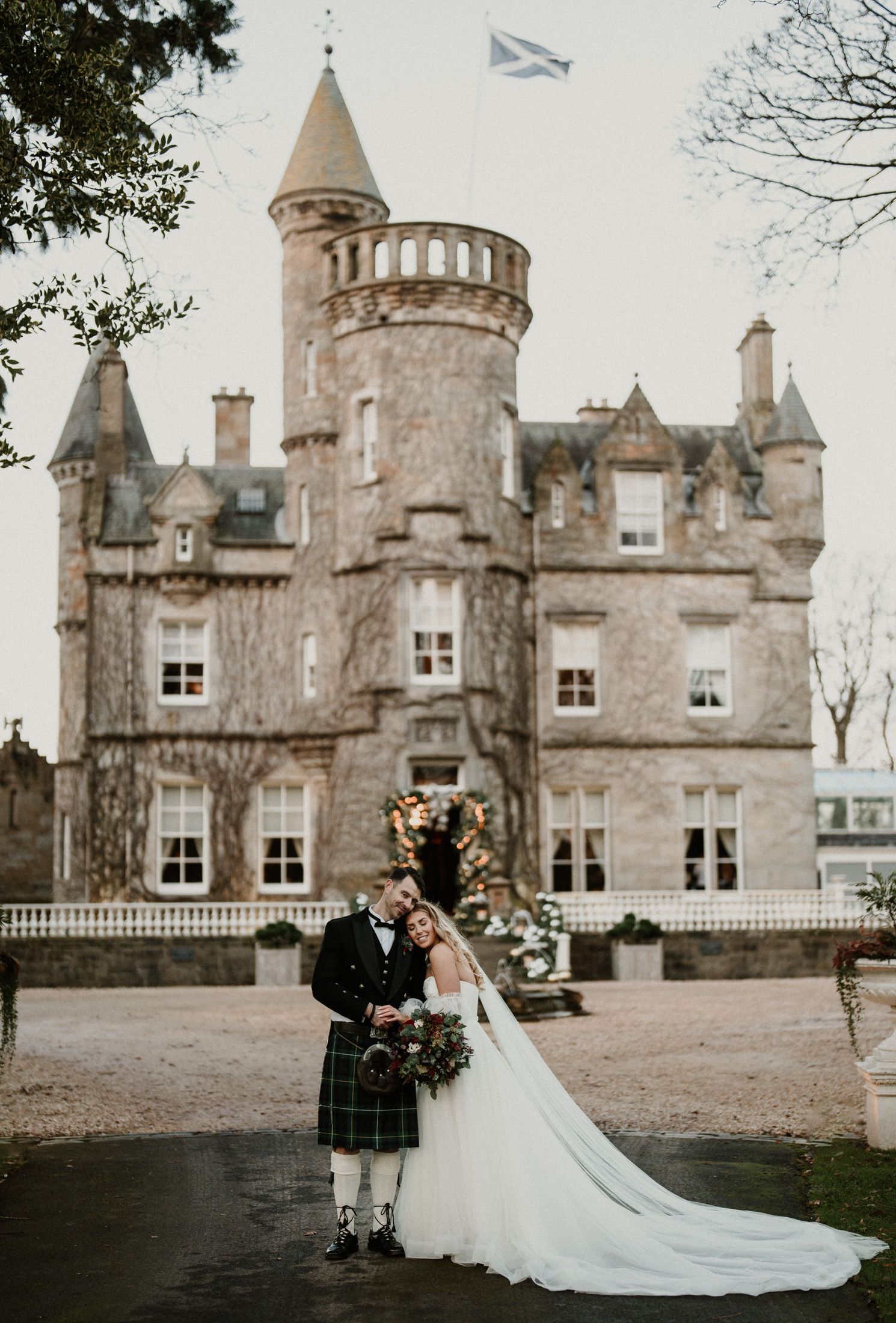 A Scottish castle wedding venue with a couple posing for portraits on the castle grounds.