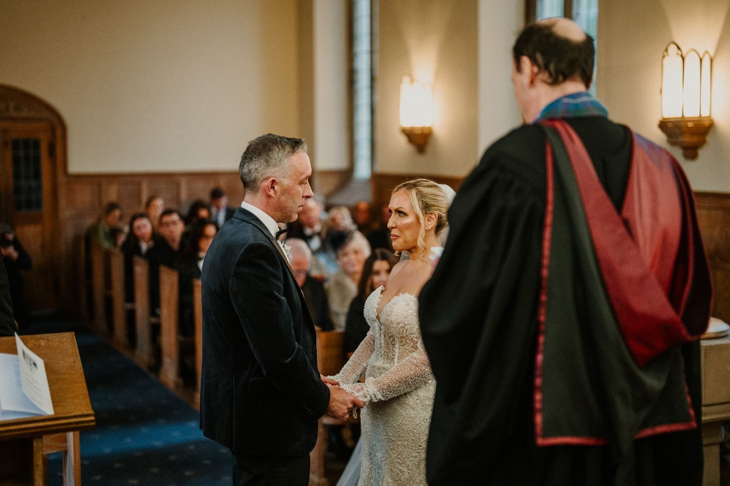 A wedding ceremony unfolds in a traditional church setting with warm lighting and elegant architecture.