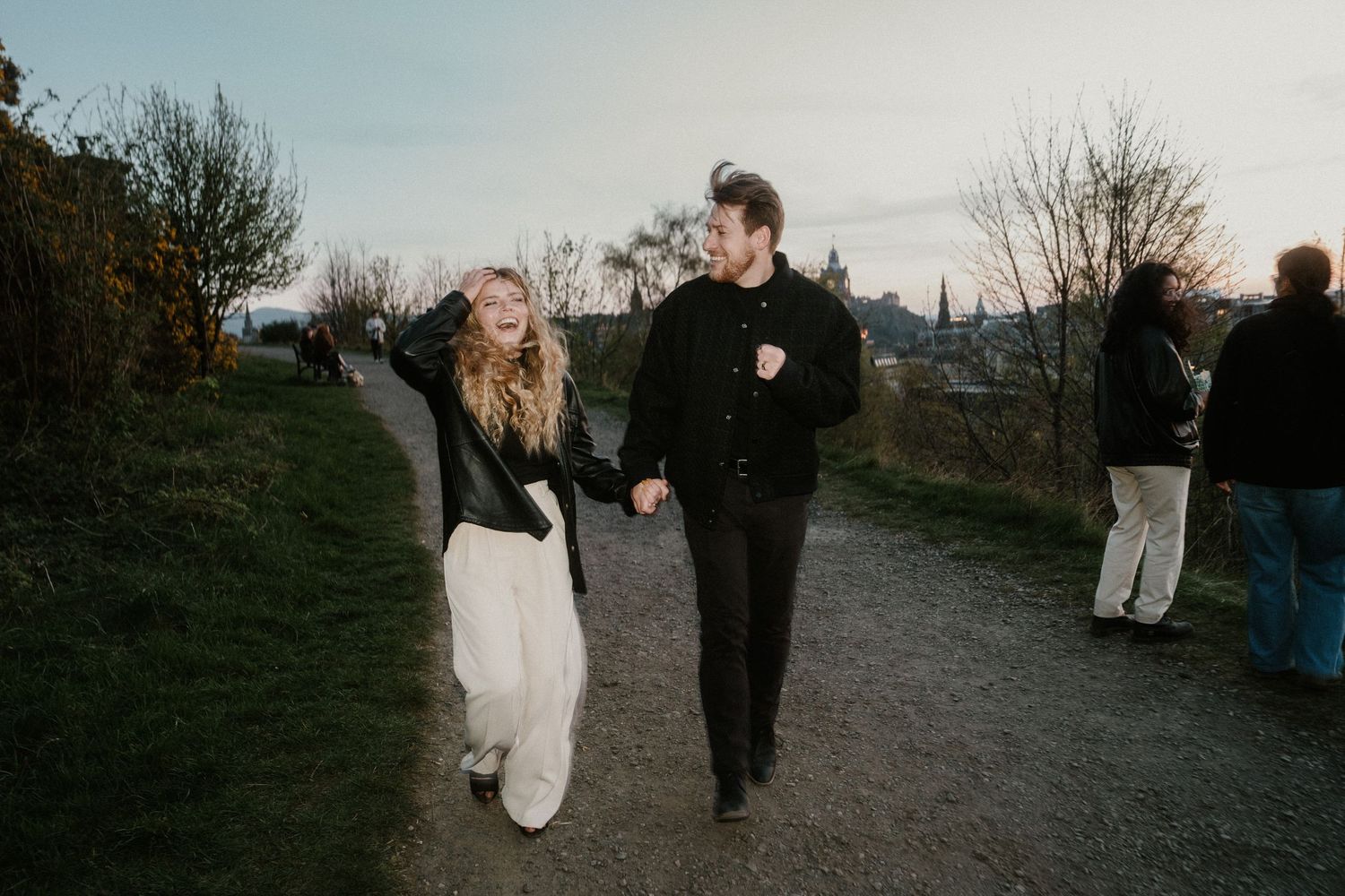Happy couple holding hands strolling along a scenic path at Calton Hill Edinburgh.