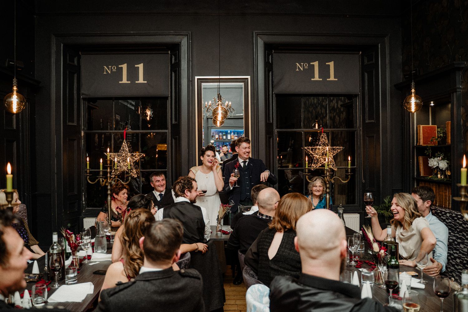 Wedding reception dinner in a dimly lit venue with elegant table settings.