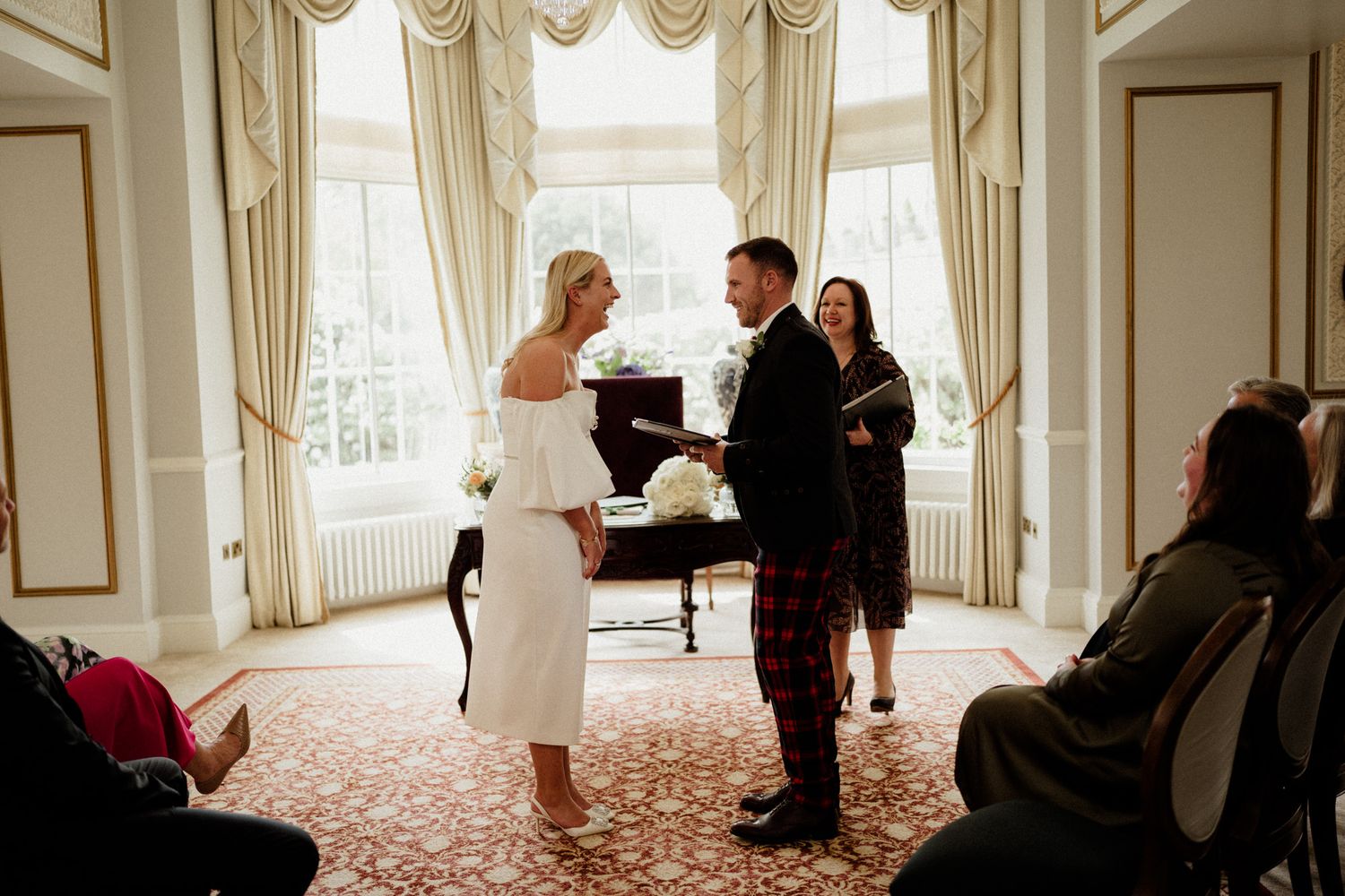 Wedding ceremony moments captured in an ornate room with elegant drapes and decor.