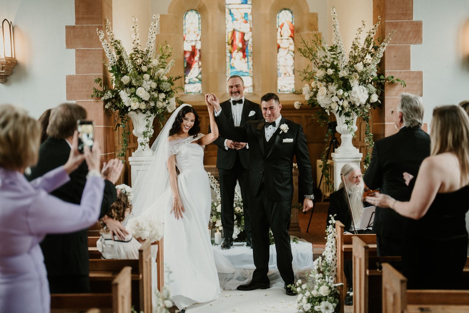 Wedding guests celebrate as the ceremony concludes in a beautifully decorated church.