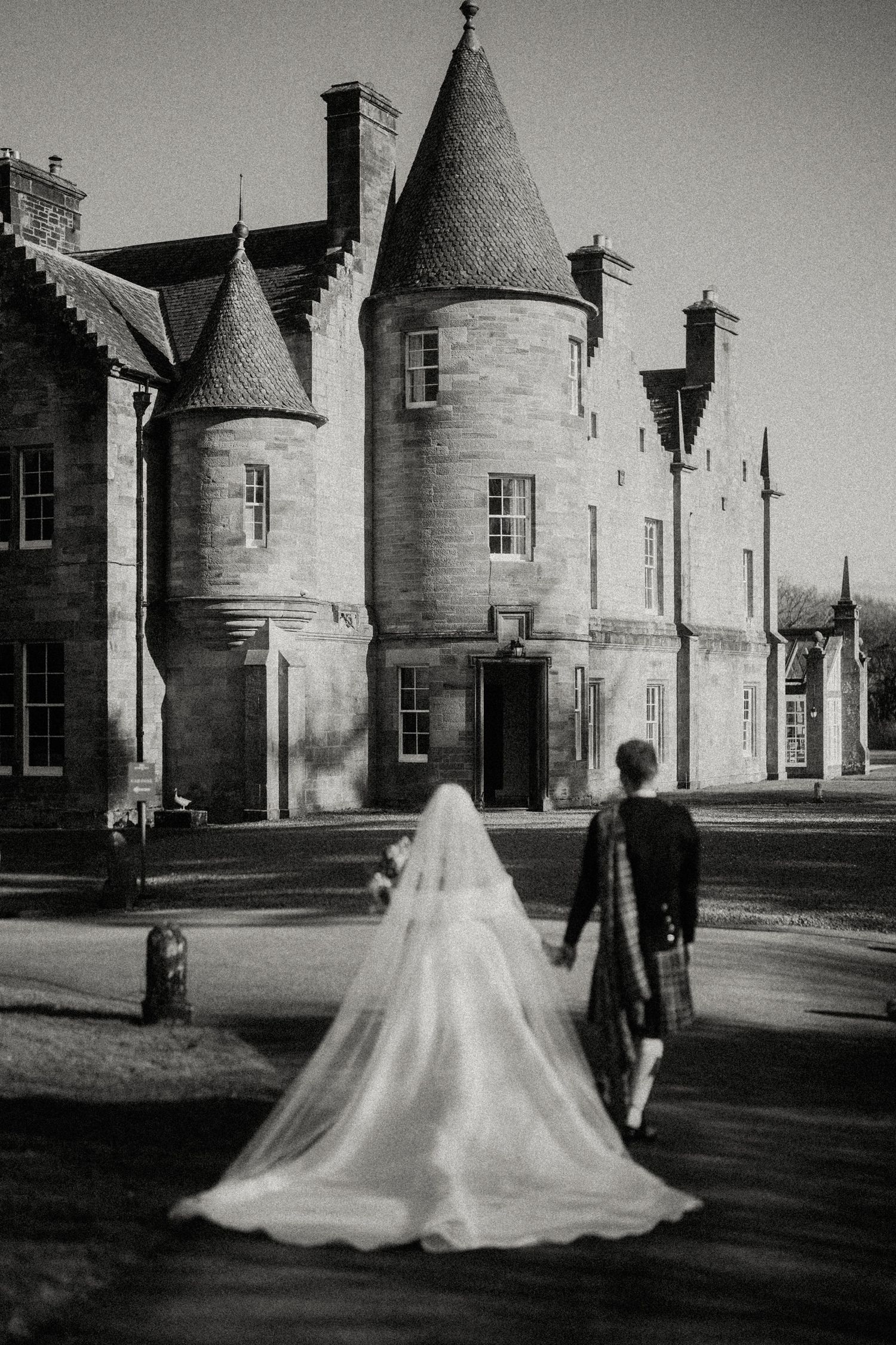 Dramatic black and white photo of bride's dress silhouette against castle architecture.