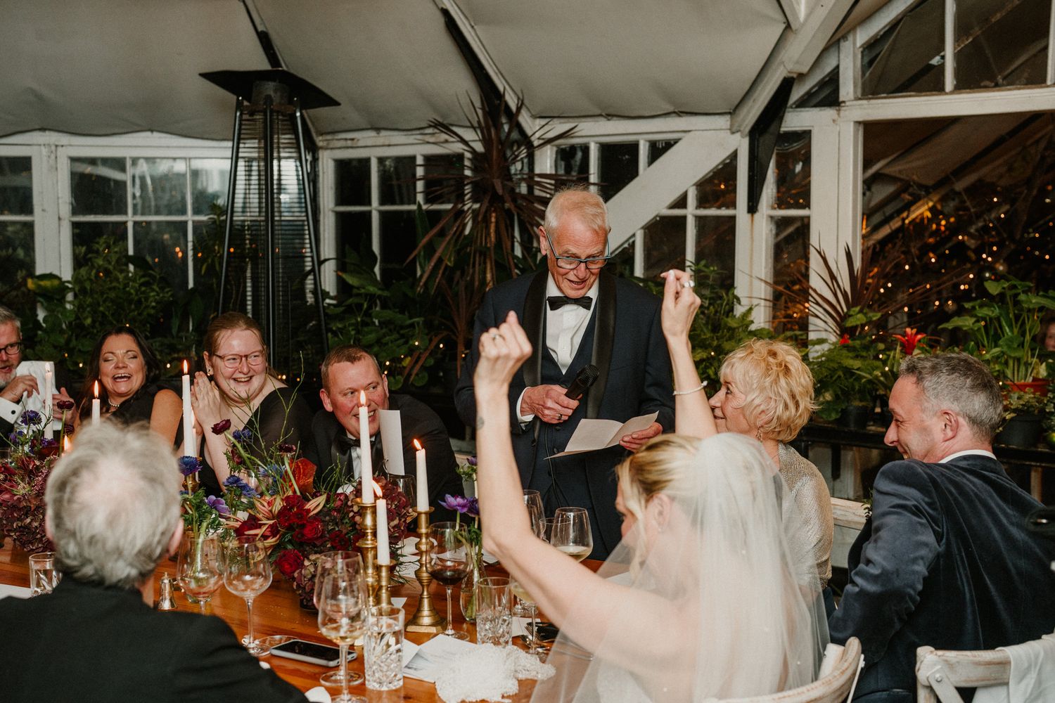 Guests celebrating with raised hands during an evening wedding reception.