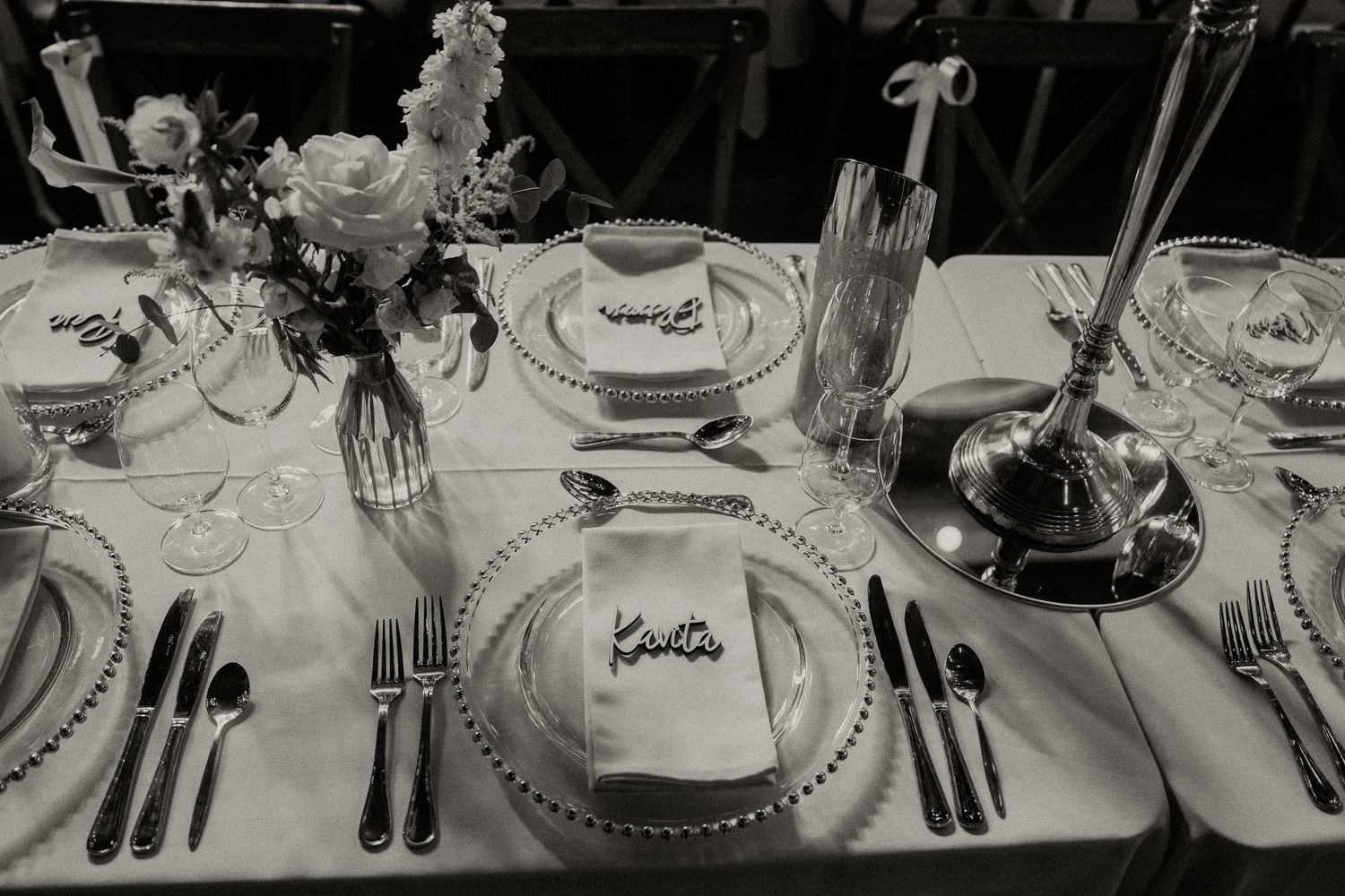 Elegant place settings with charger plates and cutlery arranged on long dining tables.