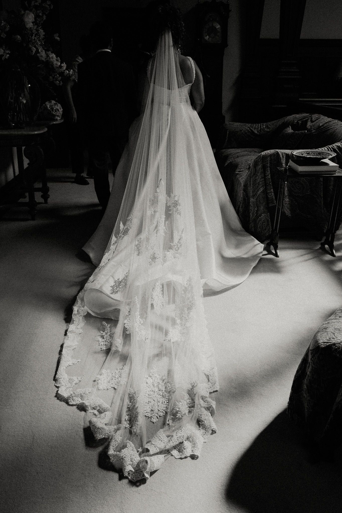 Artistic black and white photograph showing delicate lace details of a wedding dress train.