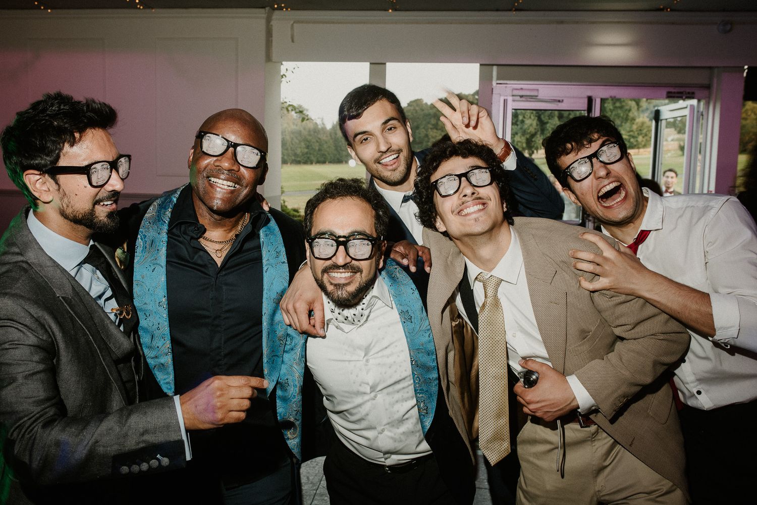 Group of wedding guests posing together with playful expressions at the reception.