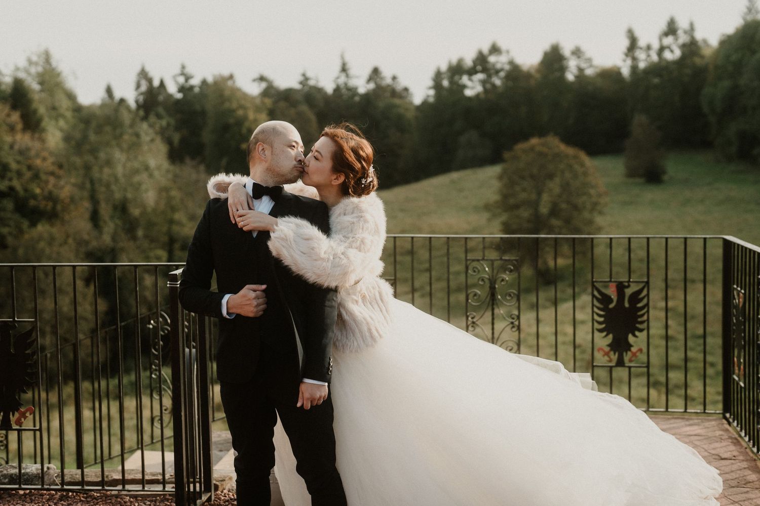 A couple shares a romantic dance outdoors with a beautiful forest backdrop.