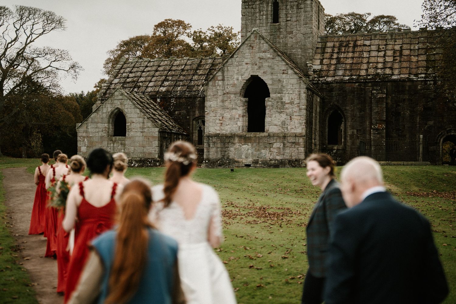 Wedding ceremony guests gather in a historic stone church with gothic arches and natural lighting.
