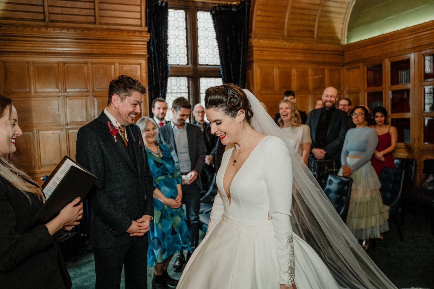 Wedding celebration in a grand wood-paneled hall with warm lighting.