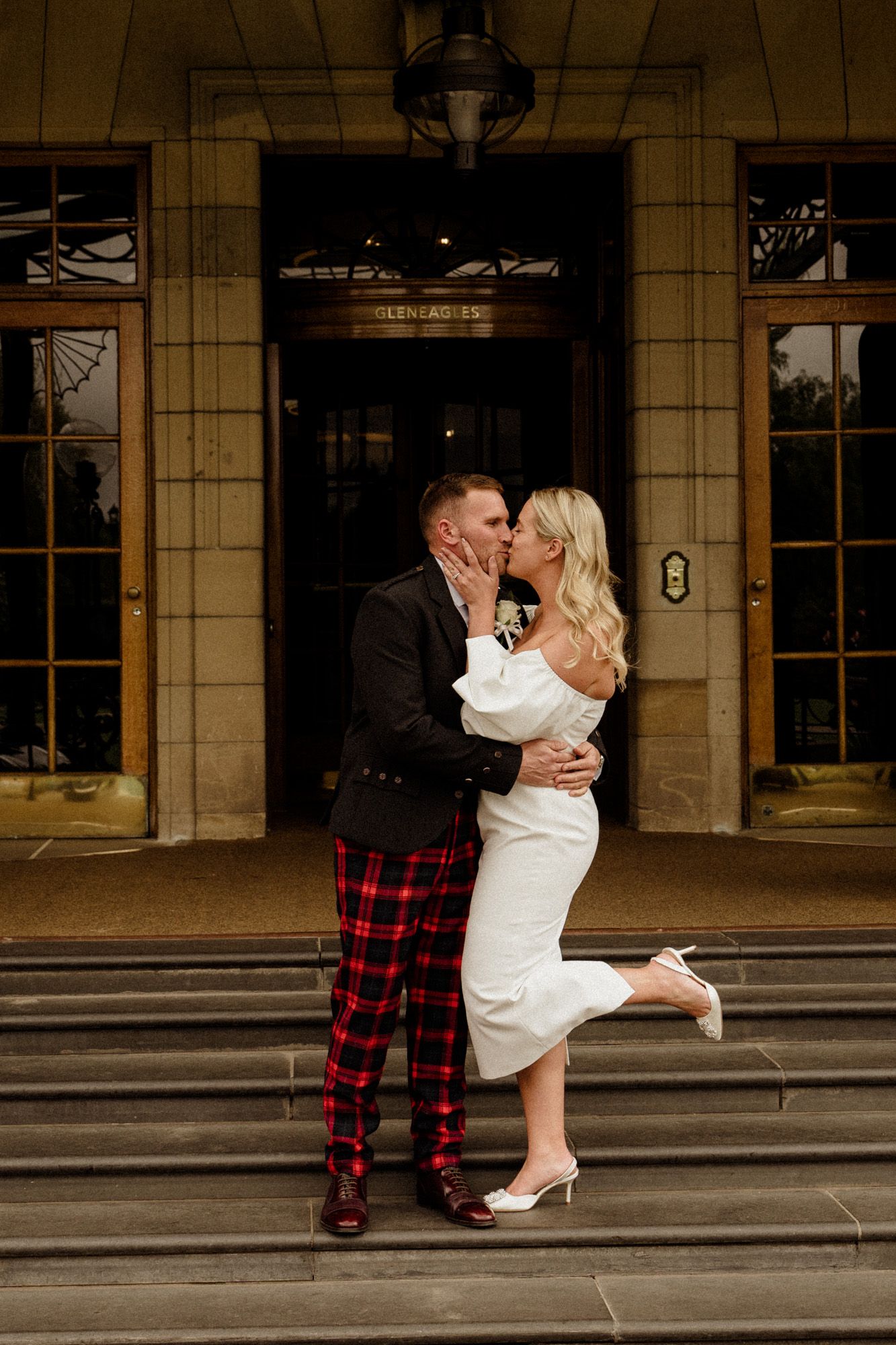 Romantic moment captured on stone steps outside elegant building.