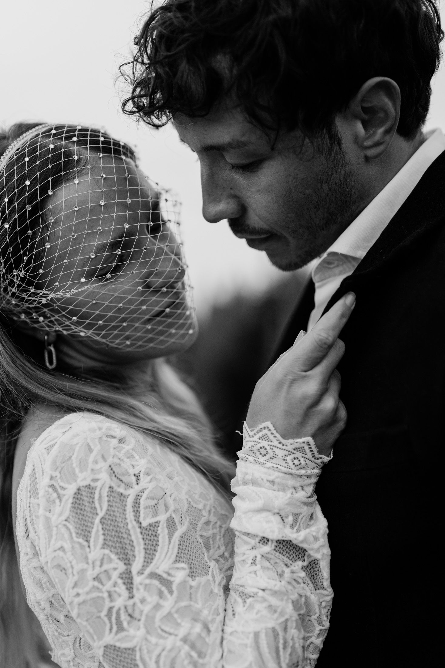 Close-up black and white shot of a tender wedding moment with delicate lace details.