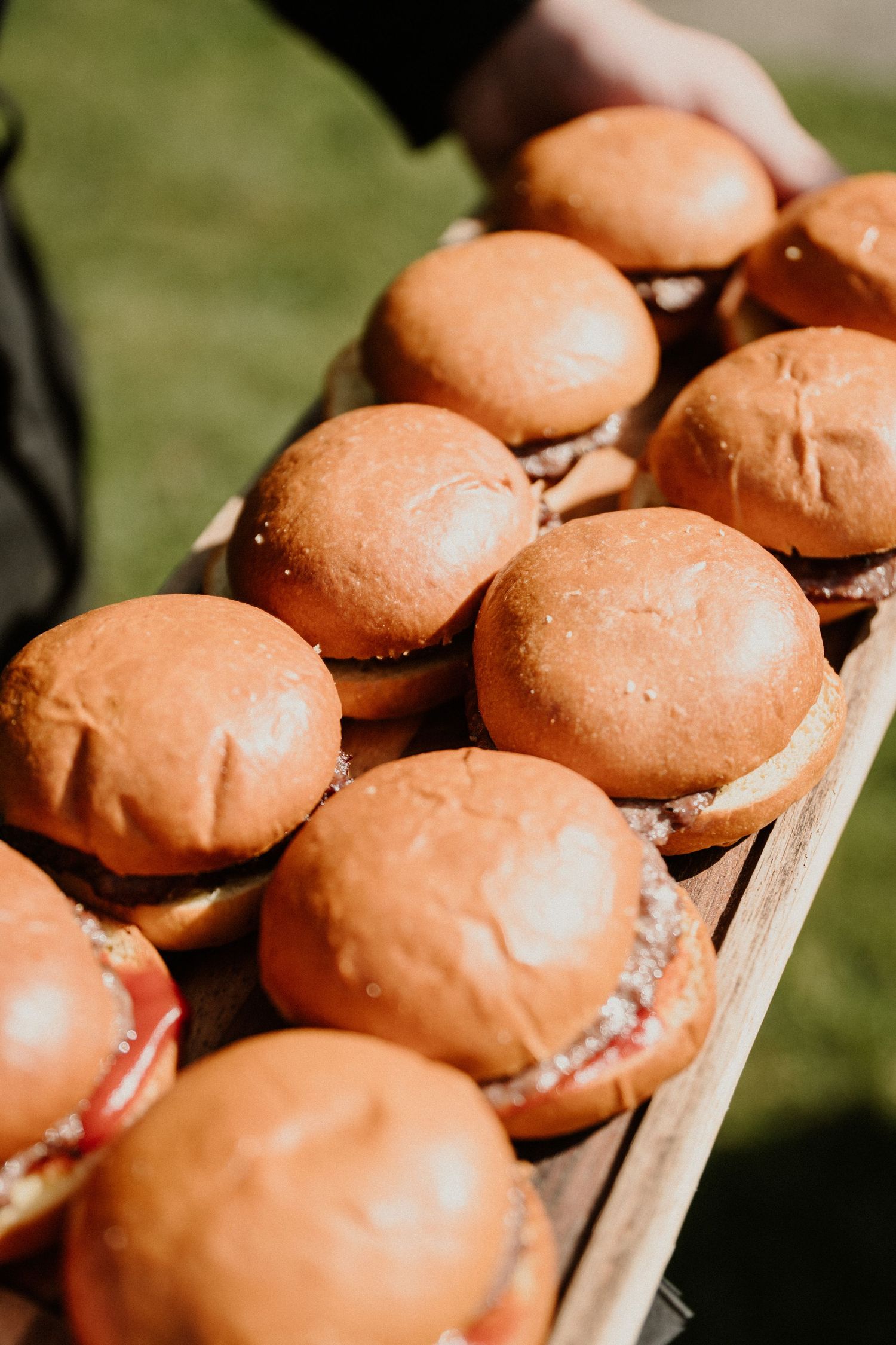 Close-up of golden hamburger buns arranged on wooden serving tray.