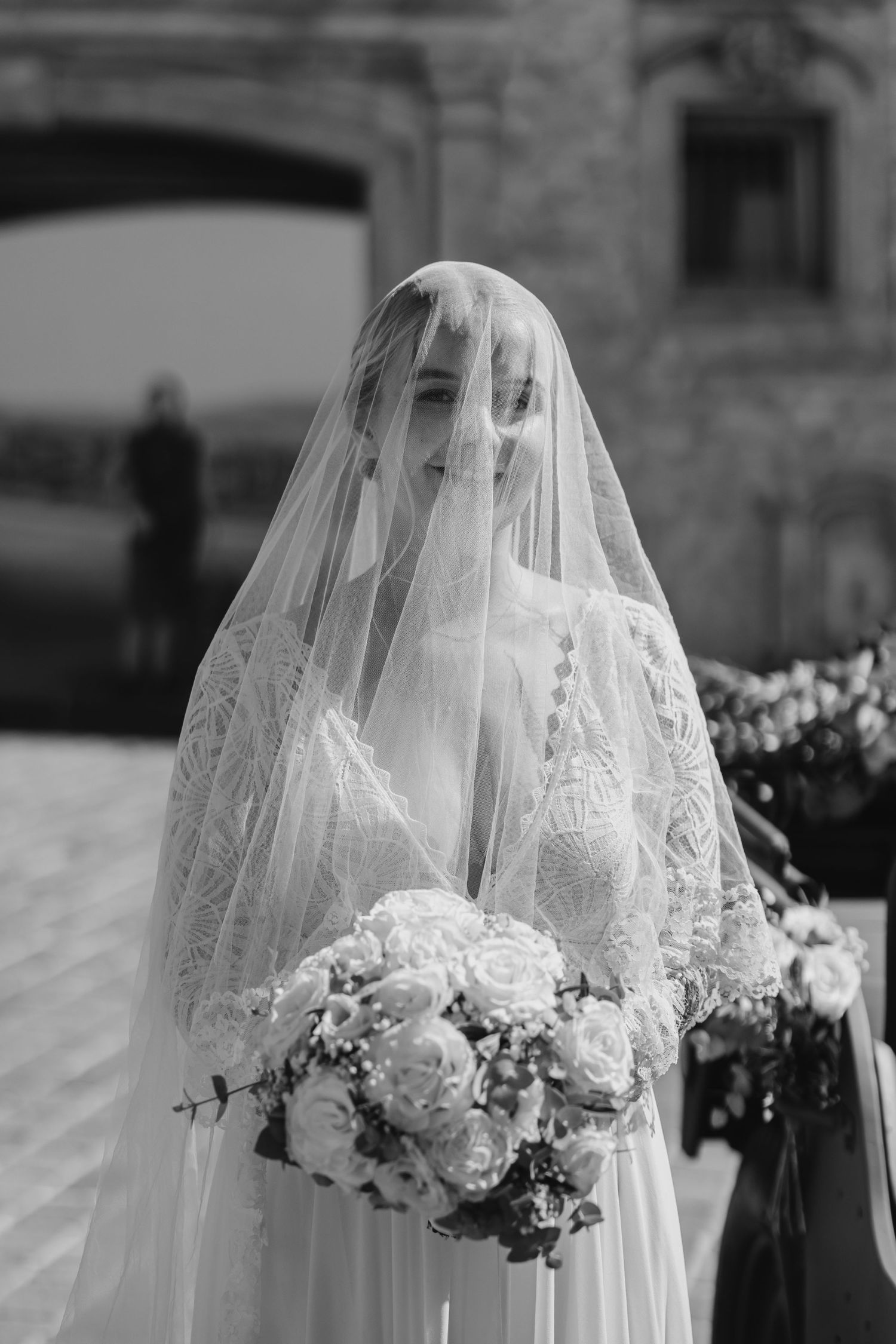 Elegant bridal veil with delicate lace details and floral bouquet in black and white.