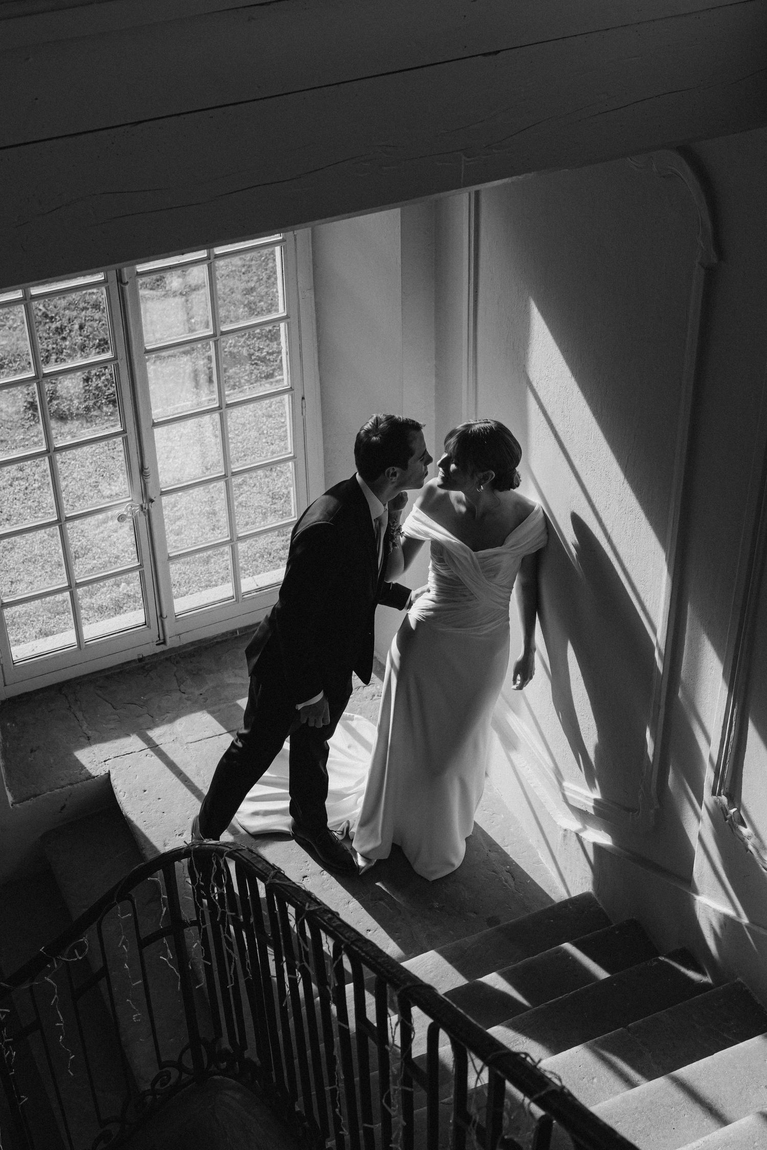 Dramatic black and white staircase scene with sunlight casting geometric shadows.