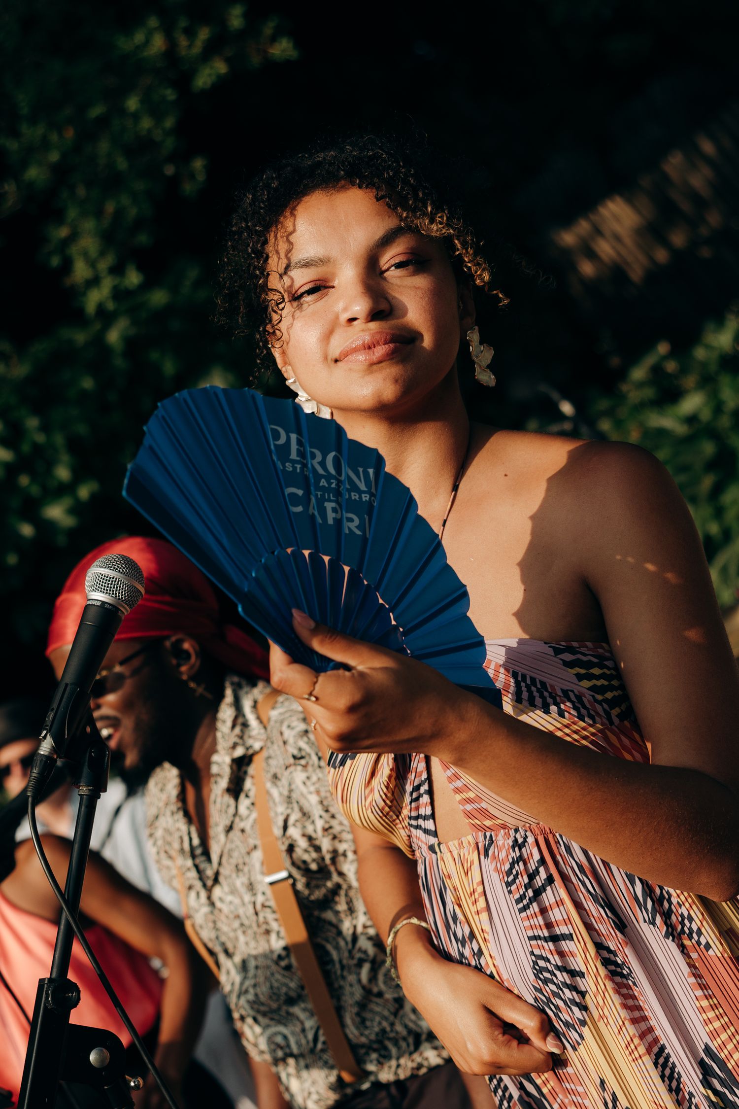 Performers with decorative fans entertaining at an outdoor evening event.