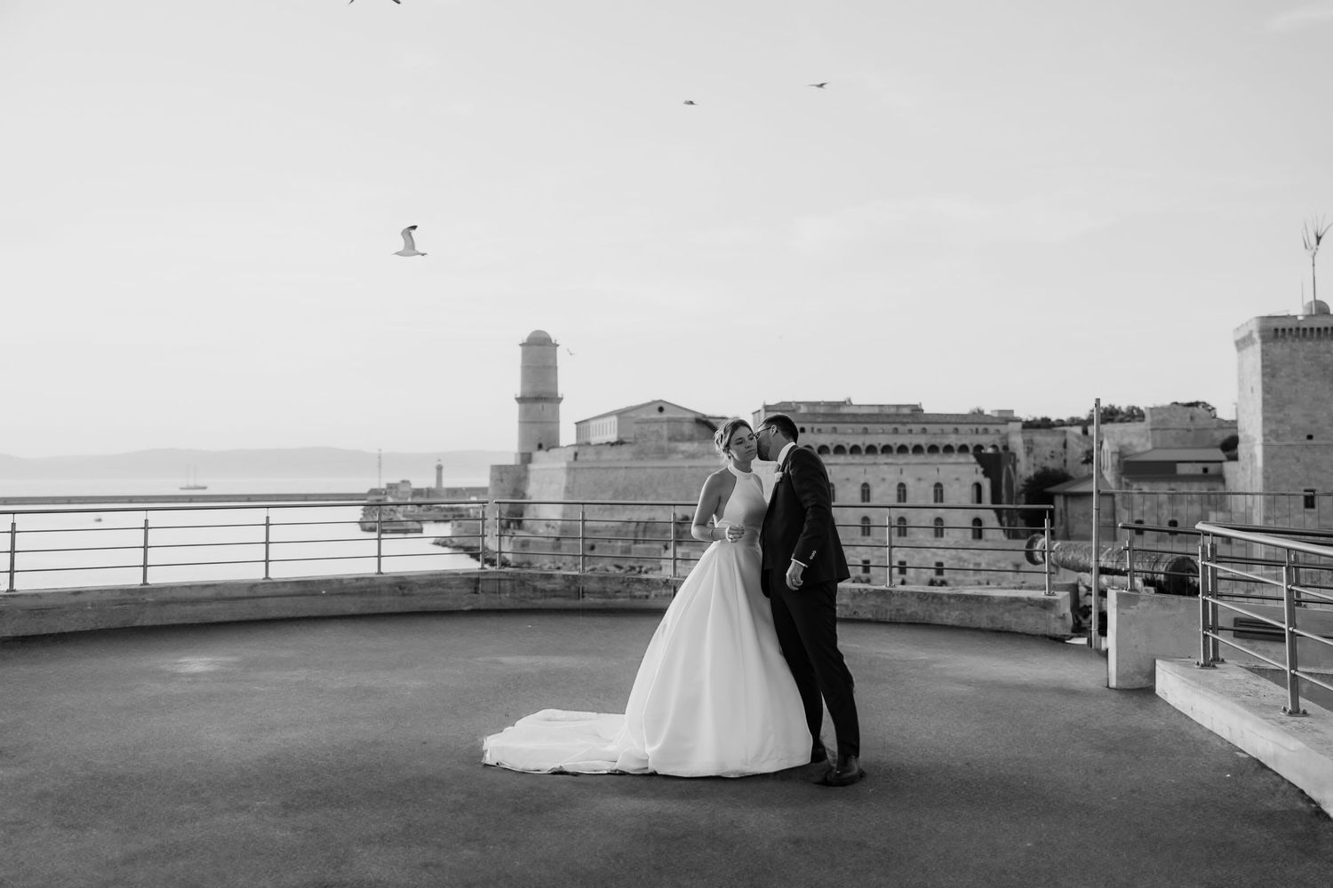 A black and white panoramic view of a seaside promenade at sunset.