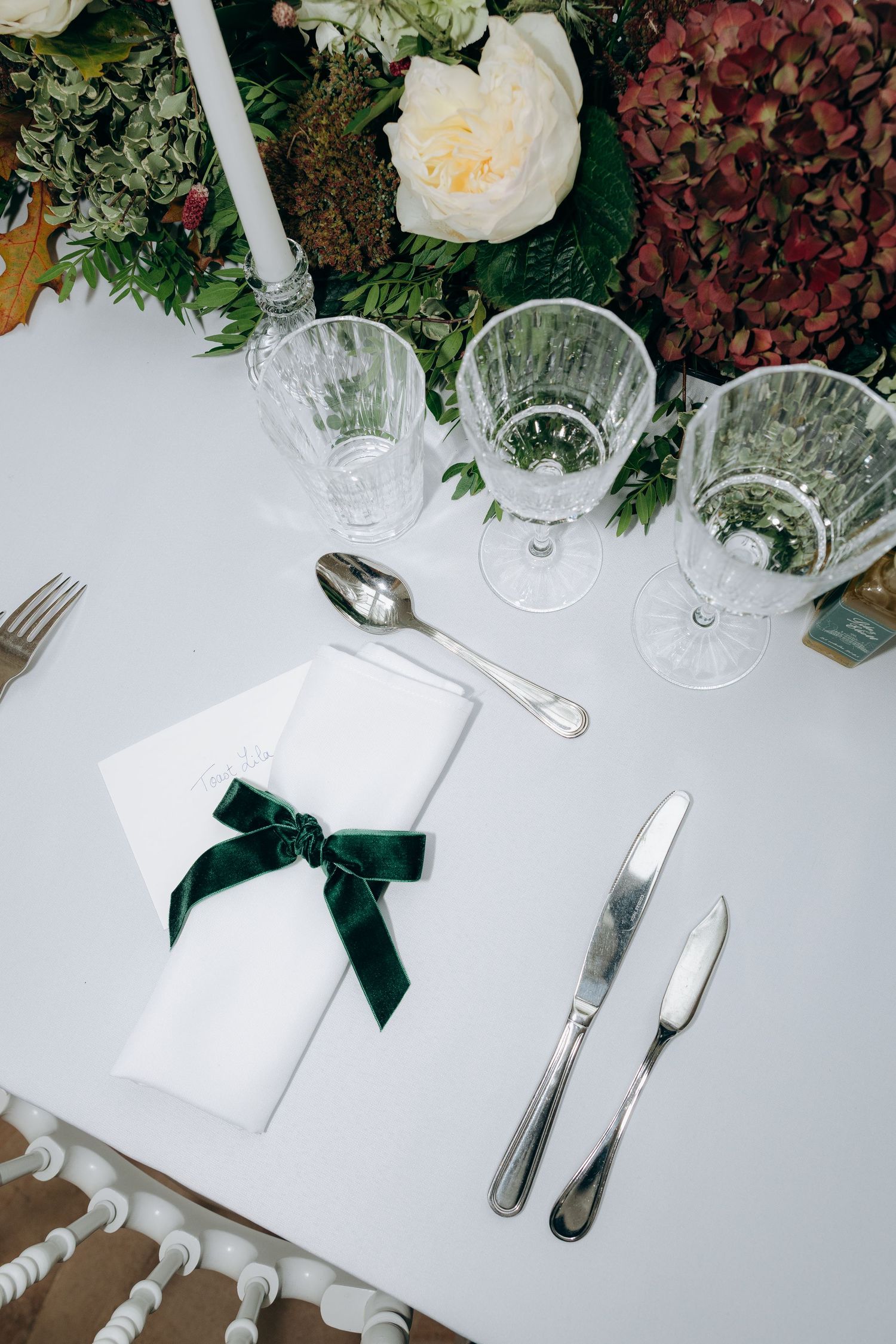 Elegant table setting with white linens, crystal glasses, and floral arrangements for a formal event.