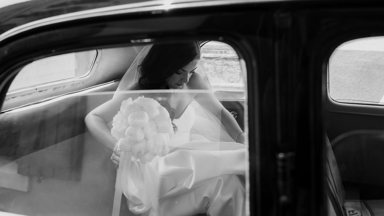 View through car windows showing glimpses of a white wedding dress.