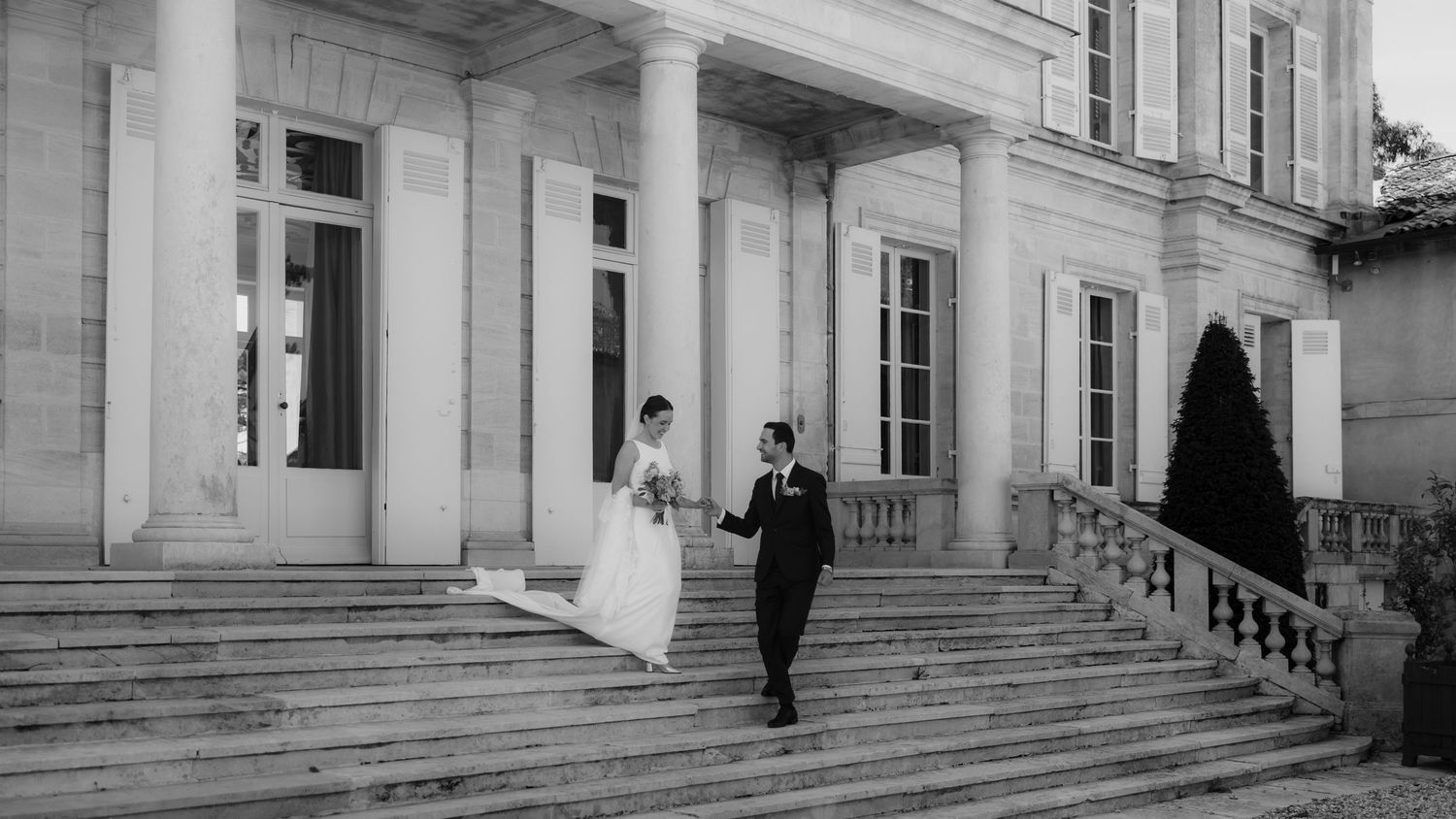 A panoramic view of a grand classical building exterior with white columns and stone steps.