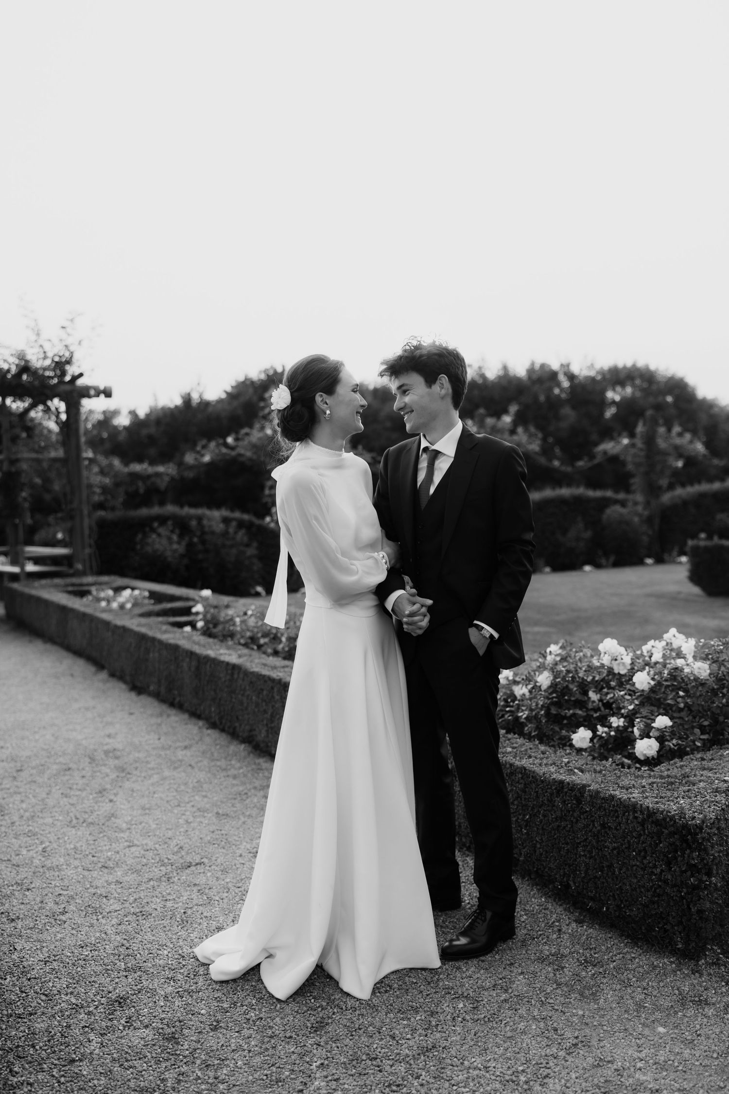 Black and white photo of a couple dancing in a garden setting.