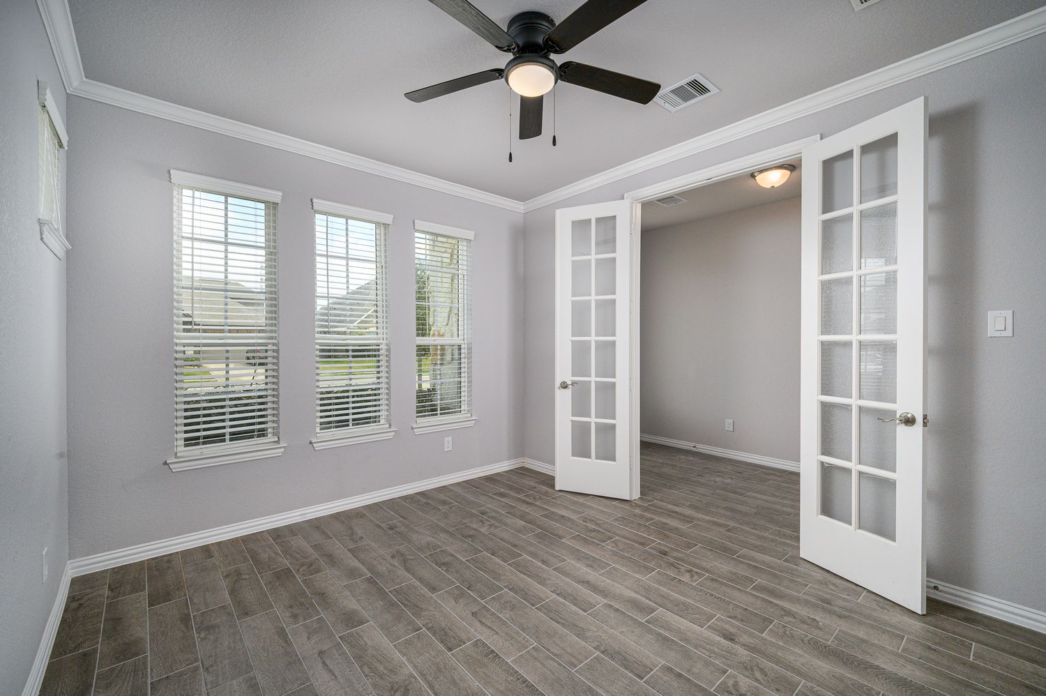 Modern living room with high ceilings, ceiling fan, and large windows letting in natural light office space in Rosharon Texas