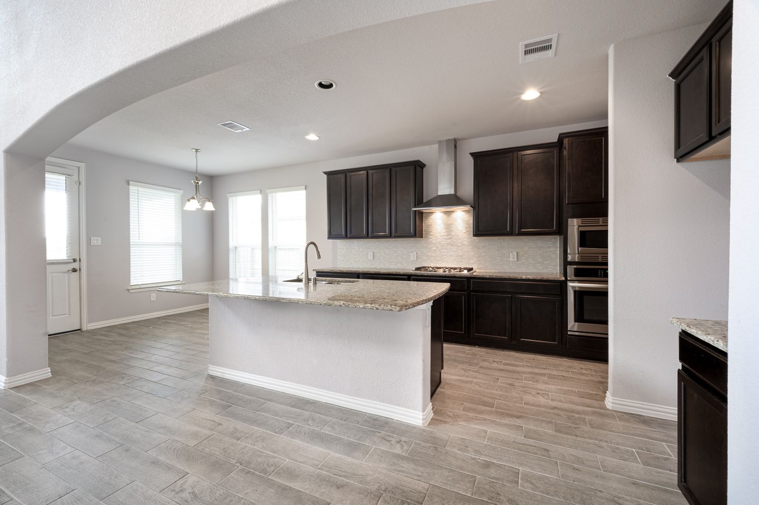 Open concept living space with modern finishes, featuring light wood floors and white walls home for sale Rosharon Texas