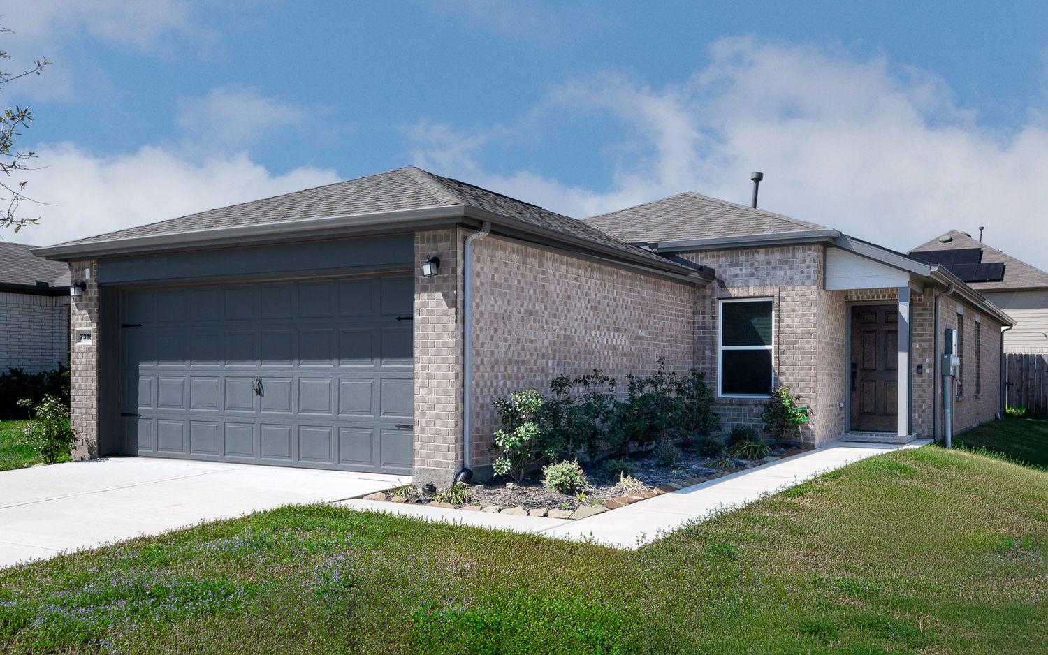 Exterior view of modern suburban homes with brick facades and manicured lawns on a sunny day Texas city Texas home for sale