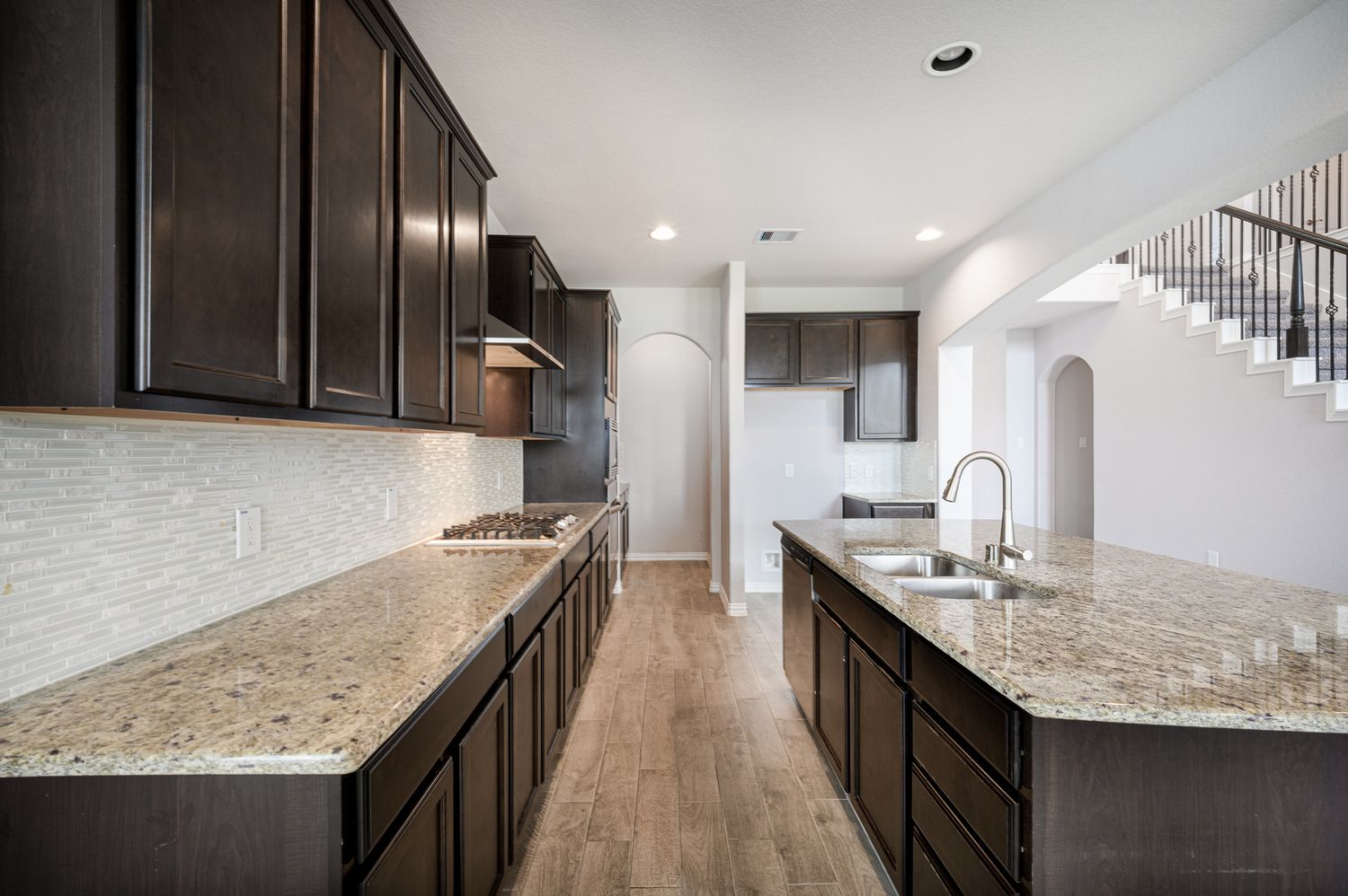 Elegant kitchen with dark cabinets, granite countertops, and stainless steel appliances at 4310 mark stone ridge lane in Rosharon Texas.