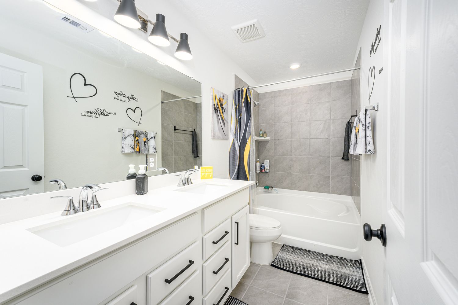 Bright modern bathroom with white cabinets and grey tile accents at 7316 Stella marina way Texas city Texas.