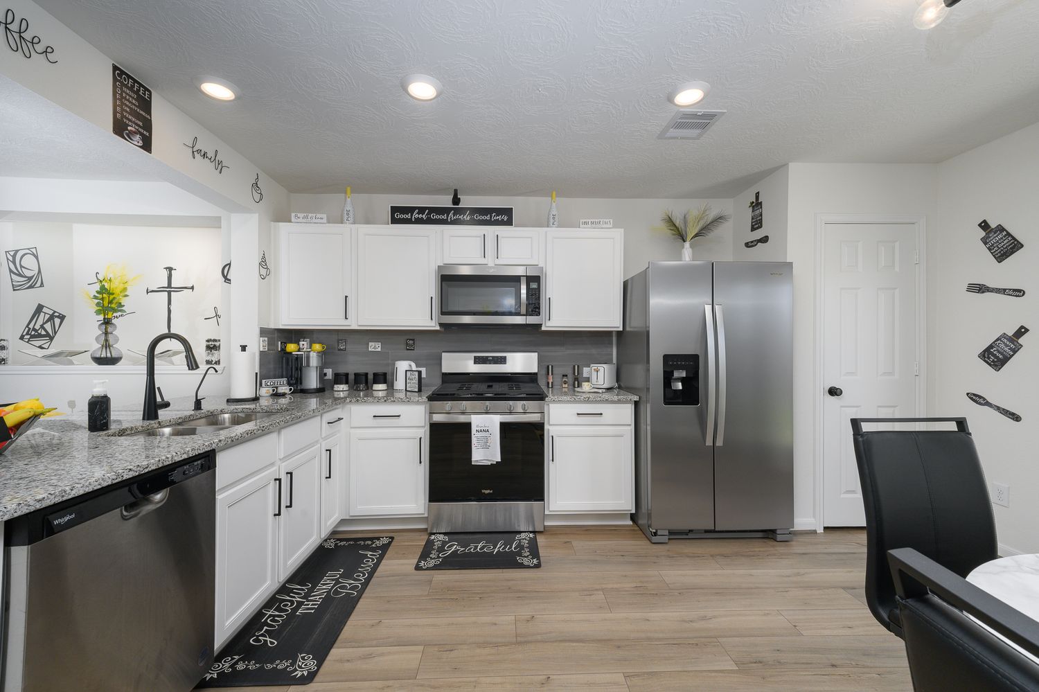Spacious modern kitchen with white cabinets, stainless steel appliances, and wood-look flooring Stella marina way Texas city Texas.