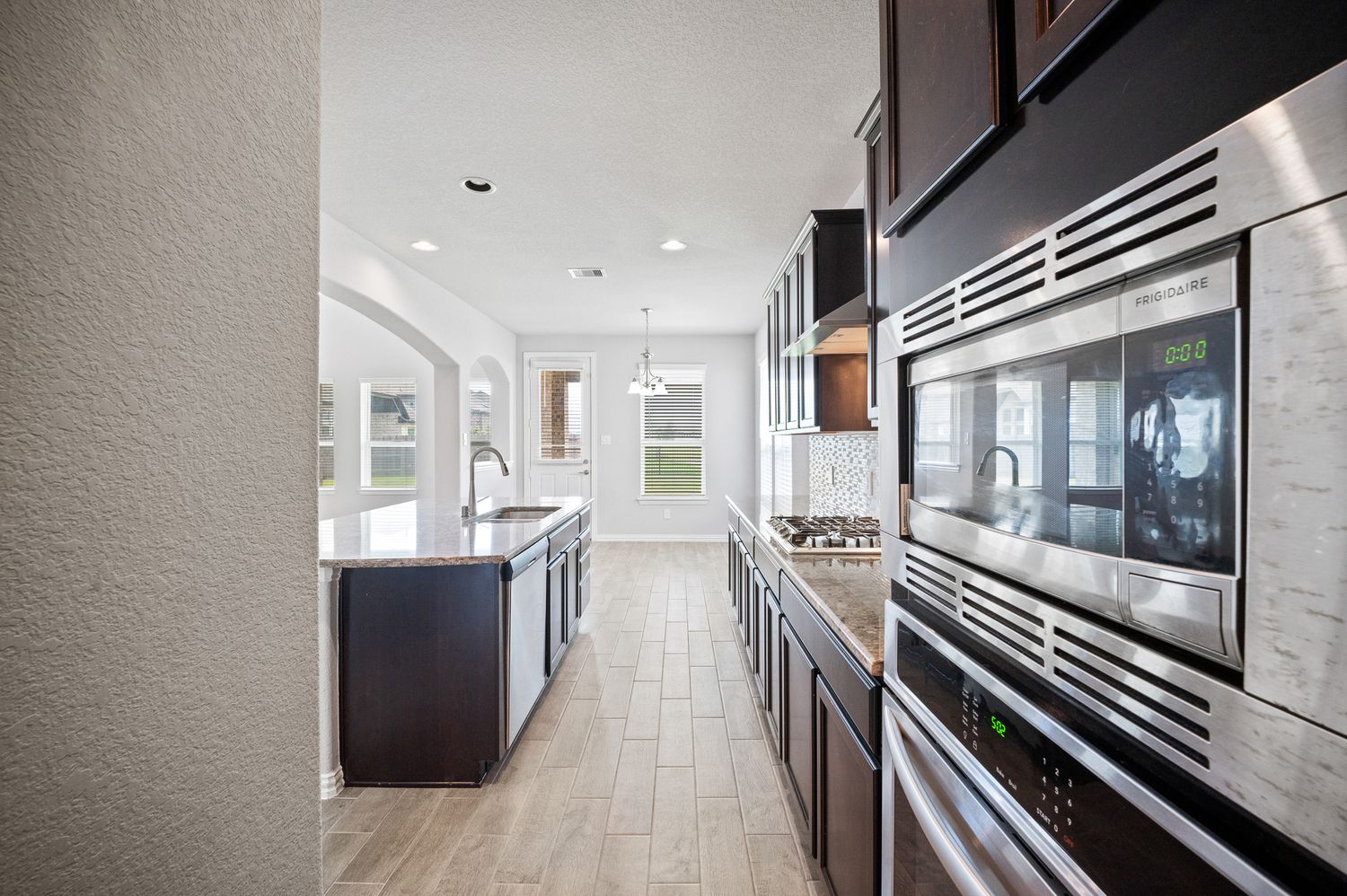 Long hallway with modern lighting and dark wood cabinets along one wall at 4310 mark stone ridge lane Rosharon Texas.