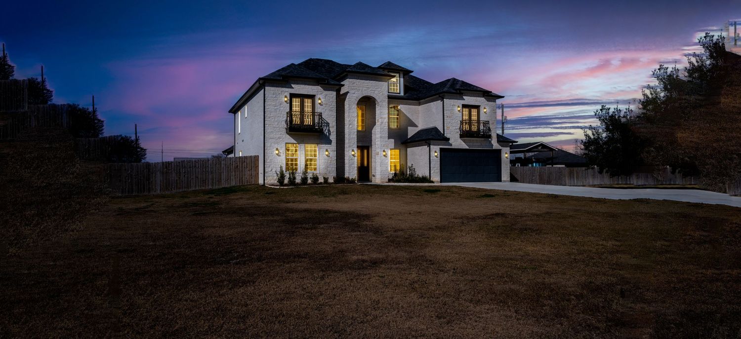 Elegant two-story house with white exterior illuminated against a vibrant twilight sky in home for sale in Dickinson texas