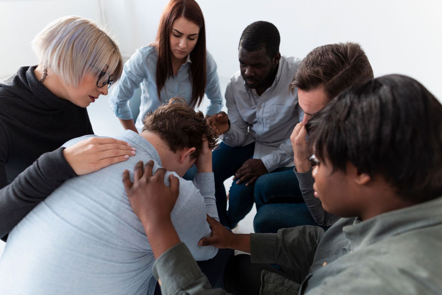 A group of people comforting someone who is visibly upset, representing emotional support, compassion, and the power of peer connection .