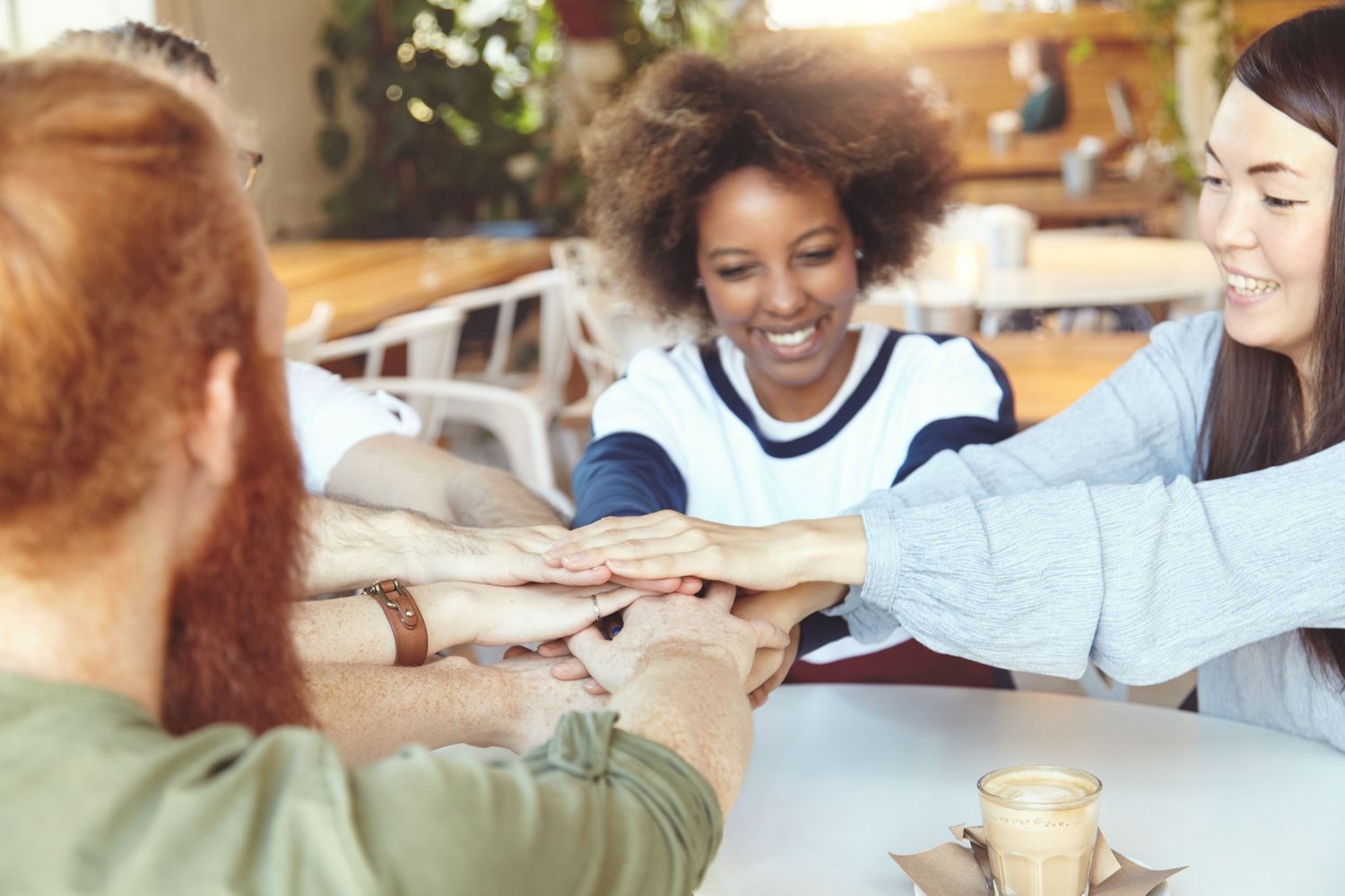 A group of young colleagues meeting in a café, representing teamwork, open communication, and supportive peer collaboration.