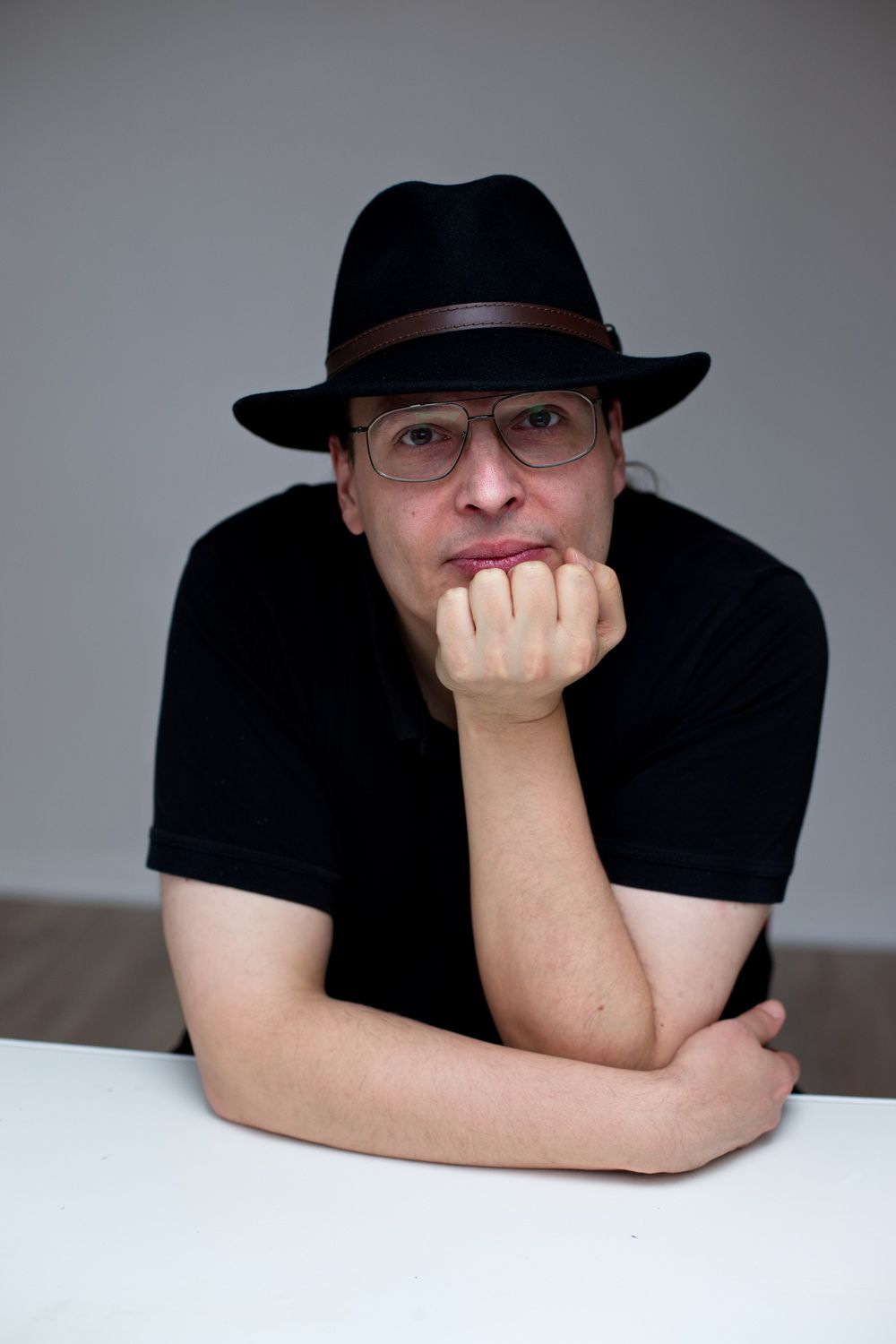 Portrait eines Mannes mit einem Hut, der seinen Kopf auf seinem Arm abstütz.