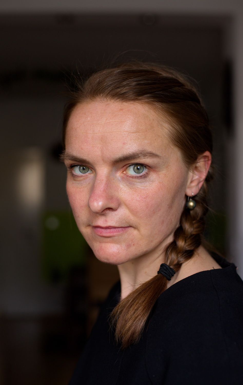 Selbstportrait der Fotografin mit einem geflochtenen Zopf und einem dunklen Hintergrund.