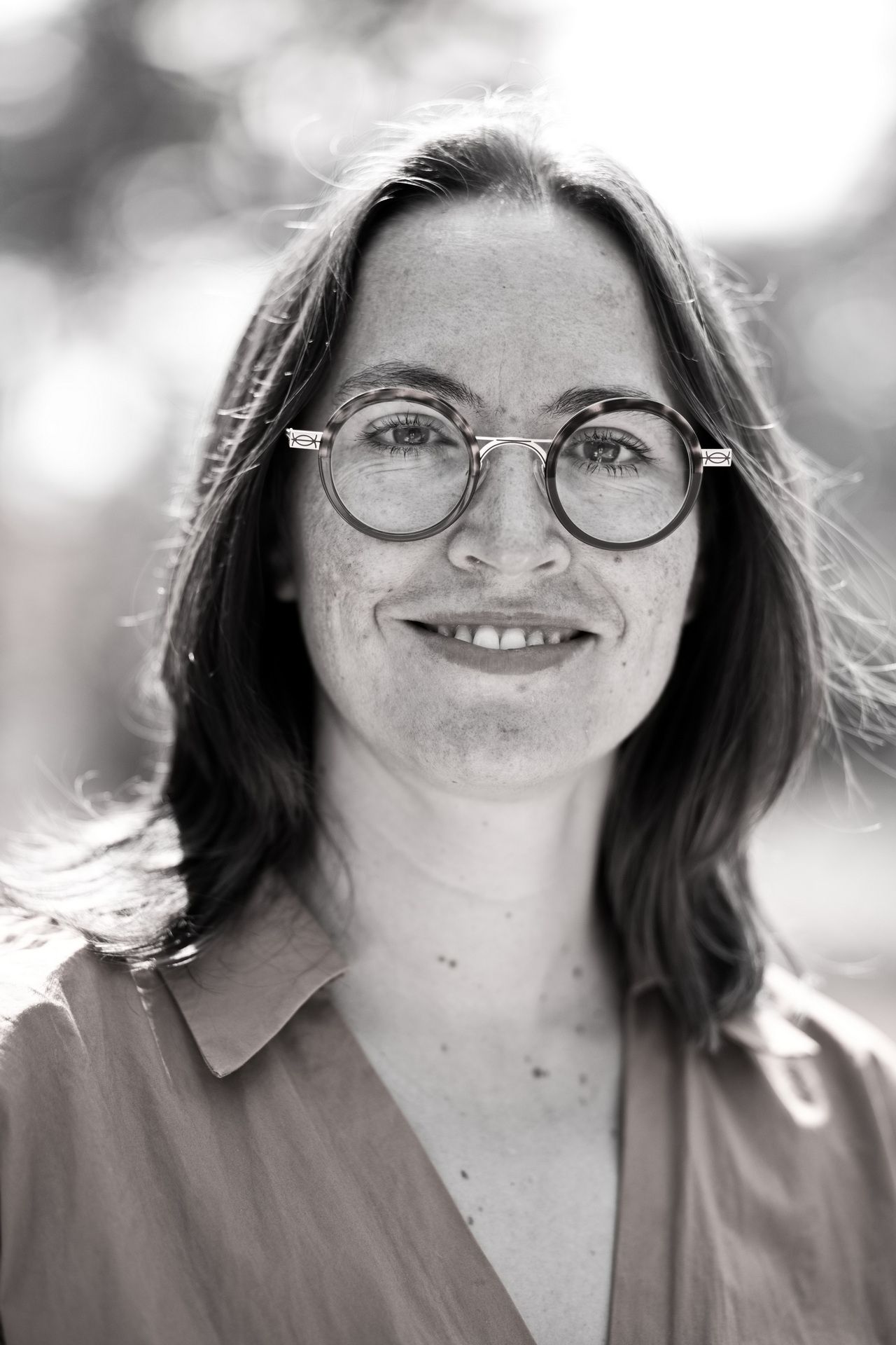 ausdrucksstarkes Portrait einer Frau mit Brille in schwarz/weiß , das Portrait wurde draußen bei sonnigem Wetter in Köln aufgenommen