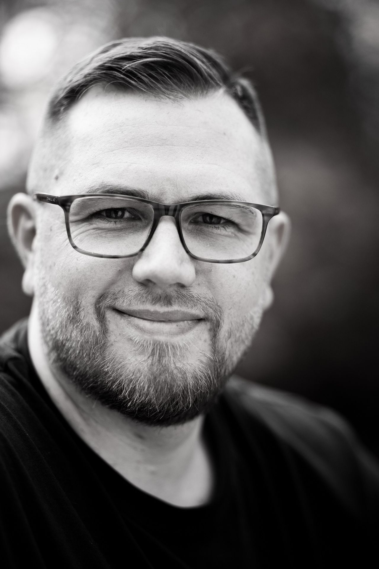 ausdrucksstarkes Portrait eines Mannes mit Brille in schwarz/weiß, das Portrait wurde draußen bei sonnigem Wetter in Langenfeld aufgenommen