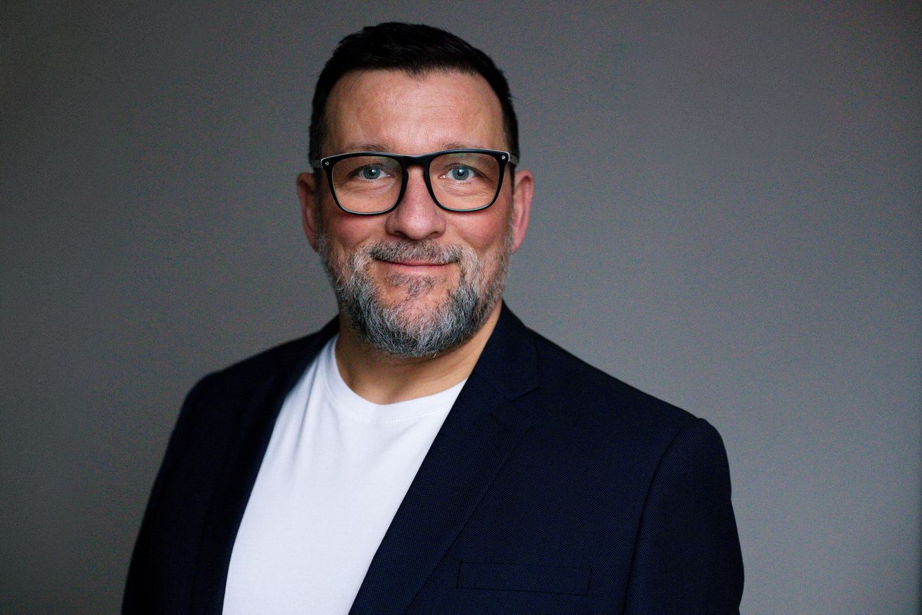 Ein Mann mit einem weißen T-Shirt und dunklem Sakko